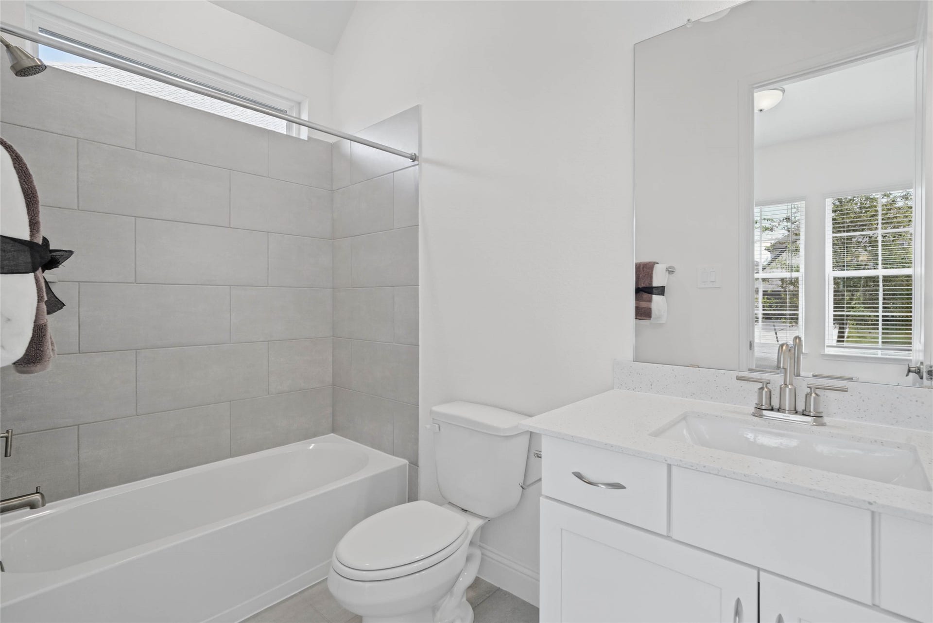 This ensuite secondary bathroom features a modern vanity, tub/shower combination with tile surround, and neutral finishes.