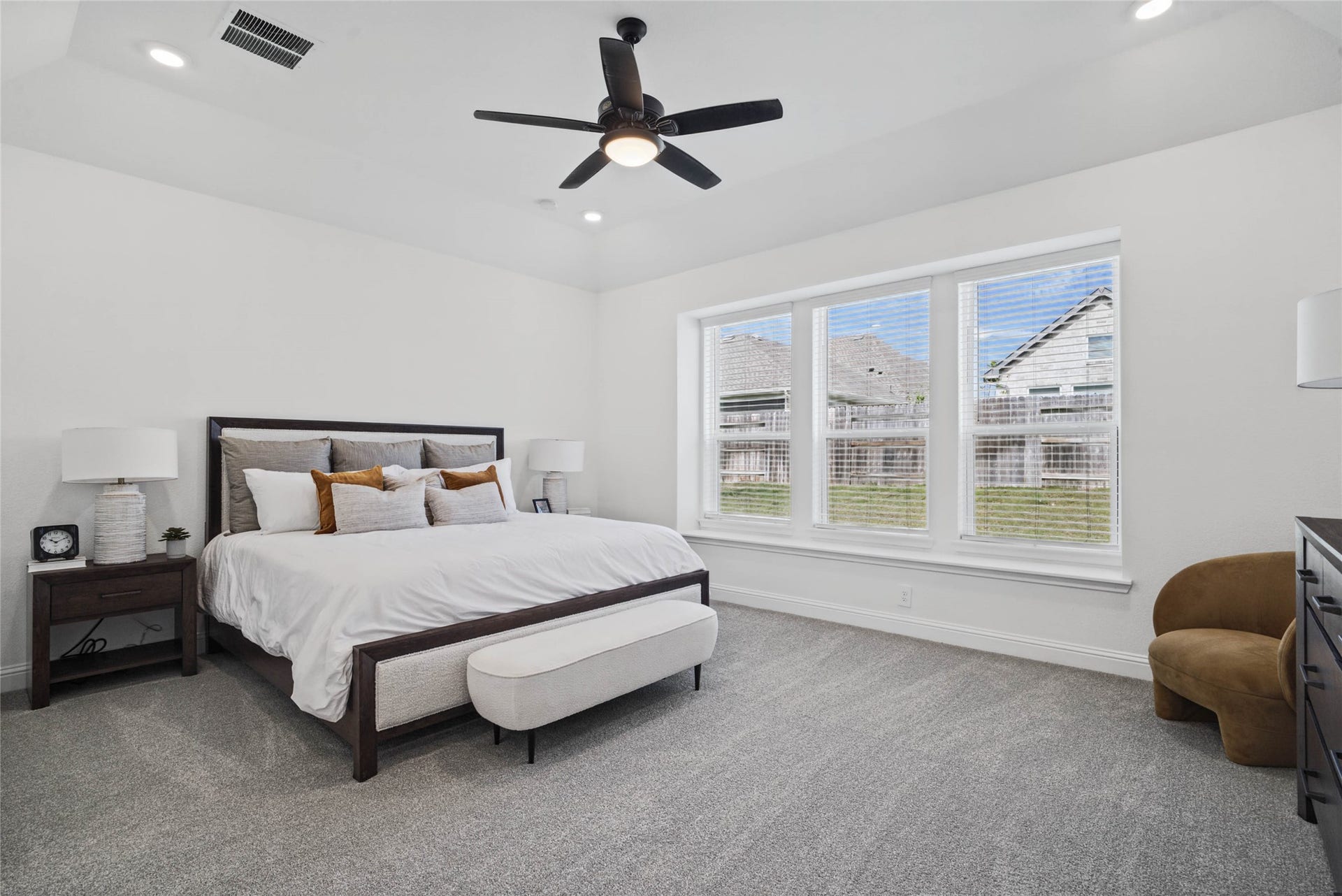Relax and unwind after a long day in this impressive primary suite! This generously sized room offers plush carpet flooring, neutral-toned paint, high ceilings with a ceiling fan, and large windows with blinds for added comfort and tranquility.