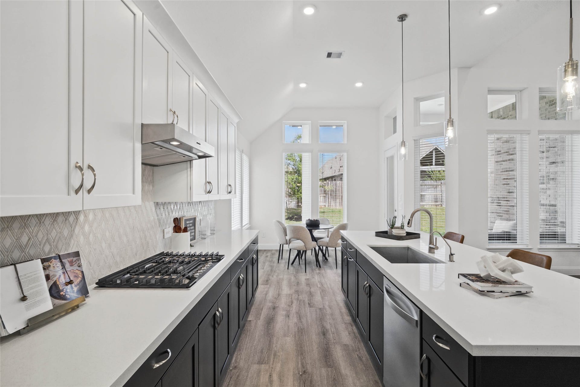 This gourmet kitchen features a modern tuxedo-style design, pairing sleek matte black base cabinets with crisp white uppers. The transitional space is anchored by a sprawling center island topped with premium quartz countertops, offering an expansive prep area and integrated stainless steel undermount sink.