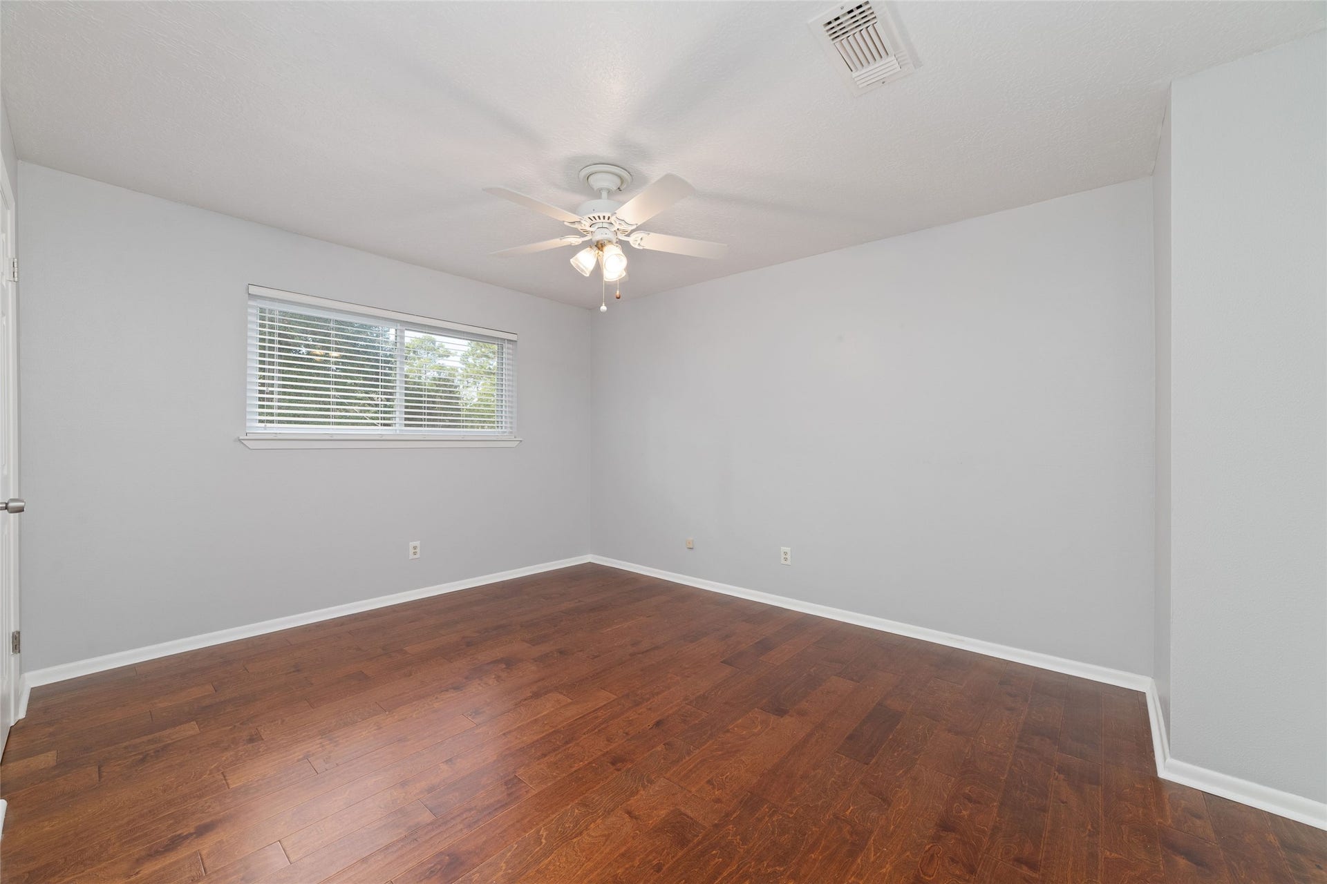 13007 New Cypress Drive, Cypress, TX 77429 Spacious upstairs bedroom with rich wood flooring, backyard views, a walk-in closet, and convenient access to a shared Jack-and-Jill bathroom. This bedroom measures appox 14x11.
