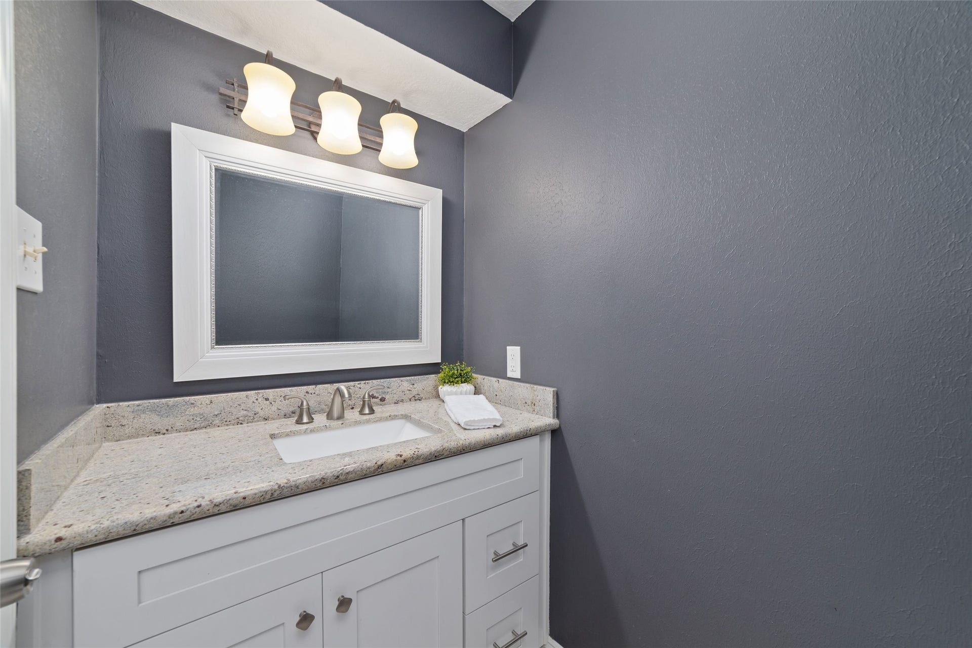 13007 New Cypress Drive, Cypress, TX 77429 Thoughtfully tucked away from the main living and dining areas, this downstairs Guest Bath offers convenience without sacrificing privacy. A granite-topped vanity, crisp white cabinetry, and rich charcoal walls create a stylish, welcoming space for guests.
