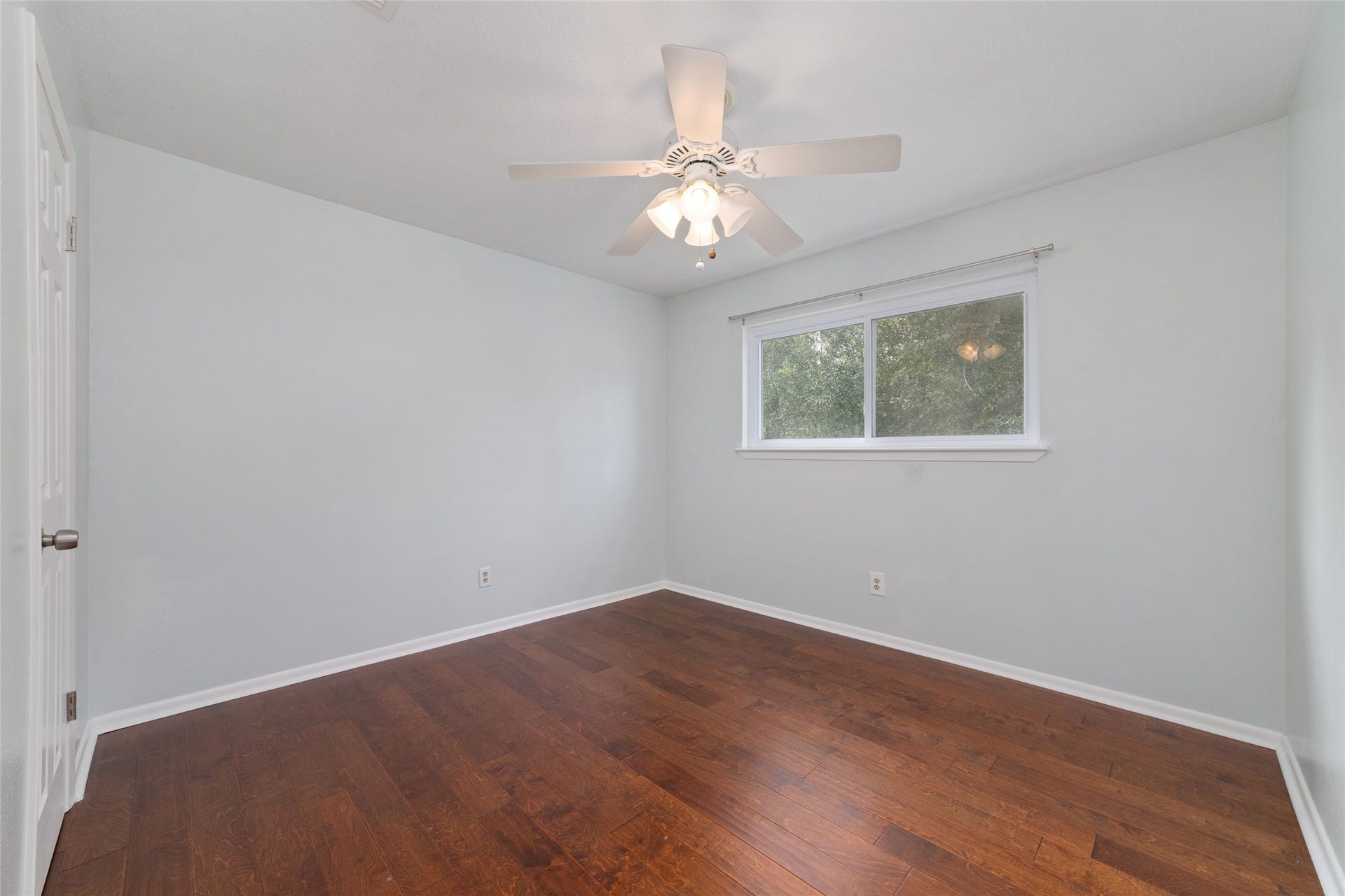 13007 New Cypress Drive, Cypress, TX 77429 Upstairs secondary bedroom, approximately 11' x 11', features rich wood flooring, a ceiling fan, a large window with views of the backyard, and a walk-in closet. An attached private full bathroom with vanity, sink, and tub/shower combination makes this an inviting retreat for family or guests.