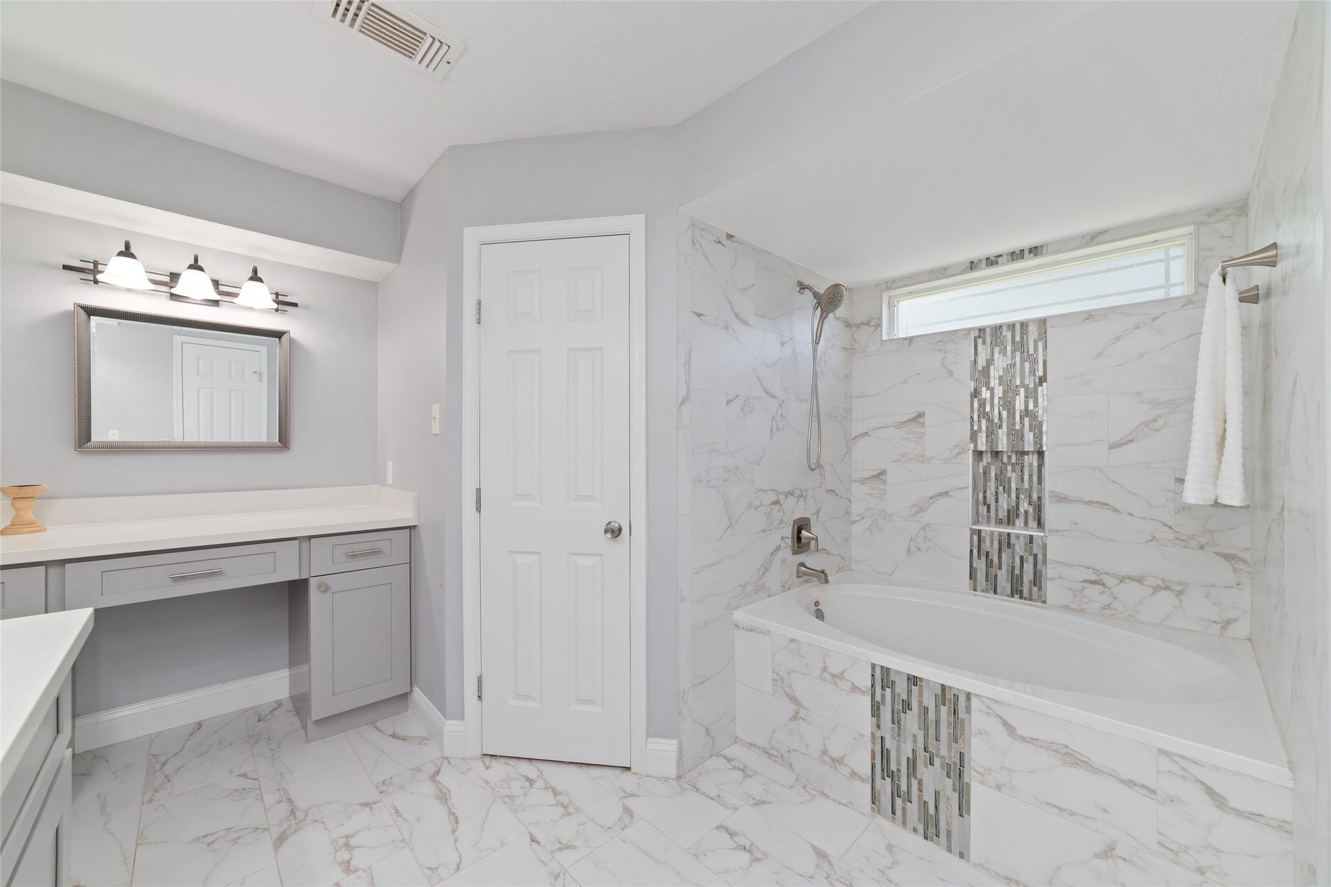 13007 New Cypress Drive, Cypress, TX 77429 Beautiful details make all the difference! The Primary Bath features a custom-tiled tub/shower combination with elegant glass mosaic accents, a convenient handheld showerhead, and natural light from the window above. A separate seated vanity offers a dedicated space for getting ready, completing this thoughtfully updated retreat.