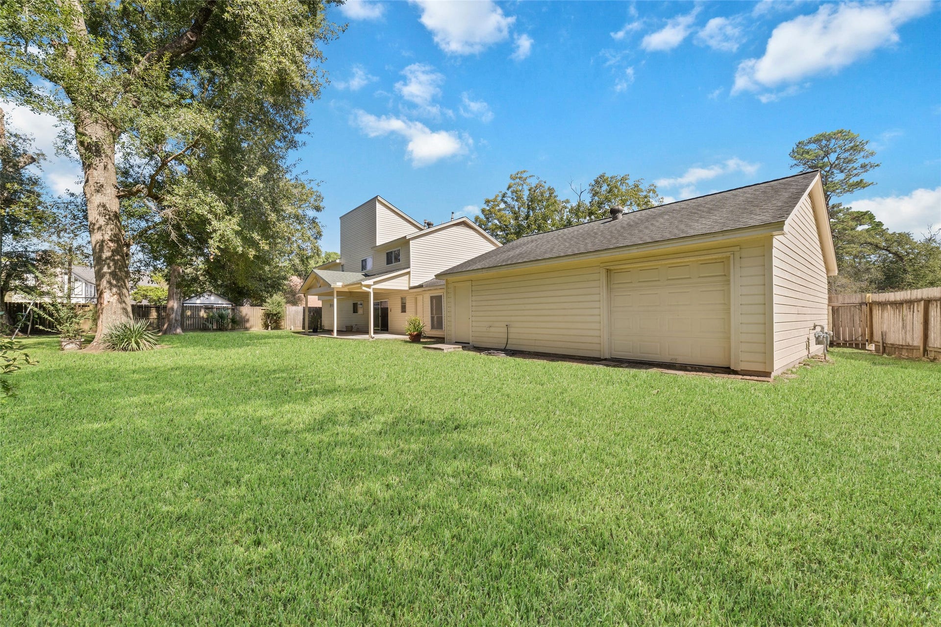 13007 New Cypress Drive, Cypress, TX 77429 More than just a place to park! The oversized garage features a convenient rear roll-up door providing direct access to the backyardperfect for moving lawn equipment, gardening supplies, or outdoor projects in and out with ease. Open both the front and rear garage doors to enjoy refreshing cross-ventilation while working on hobbies or weekend projects