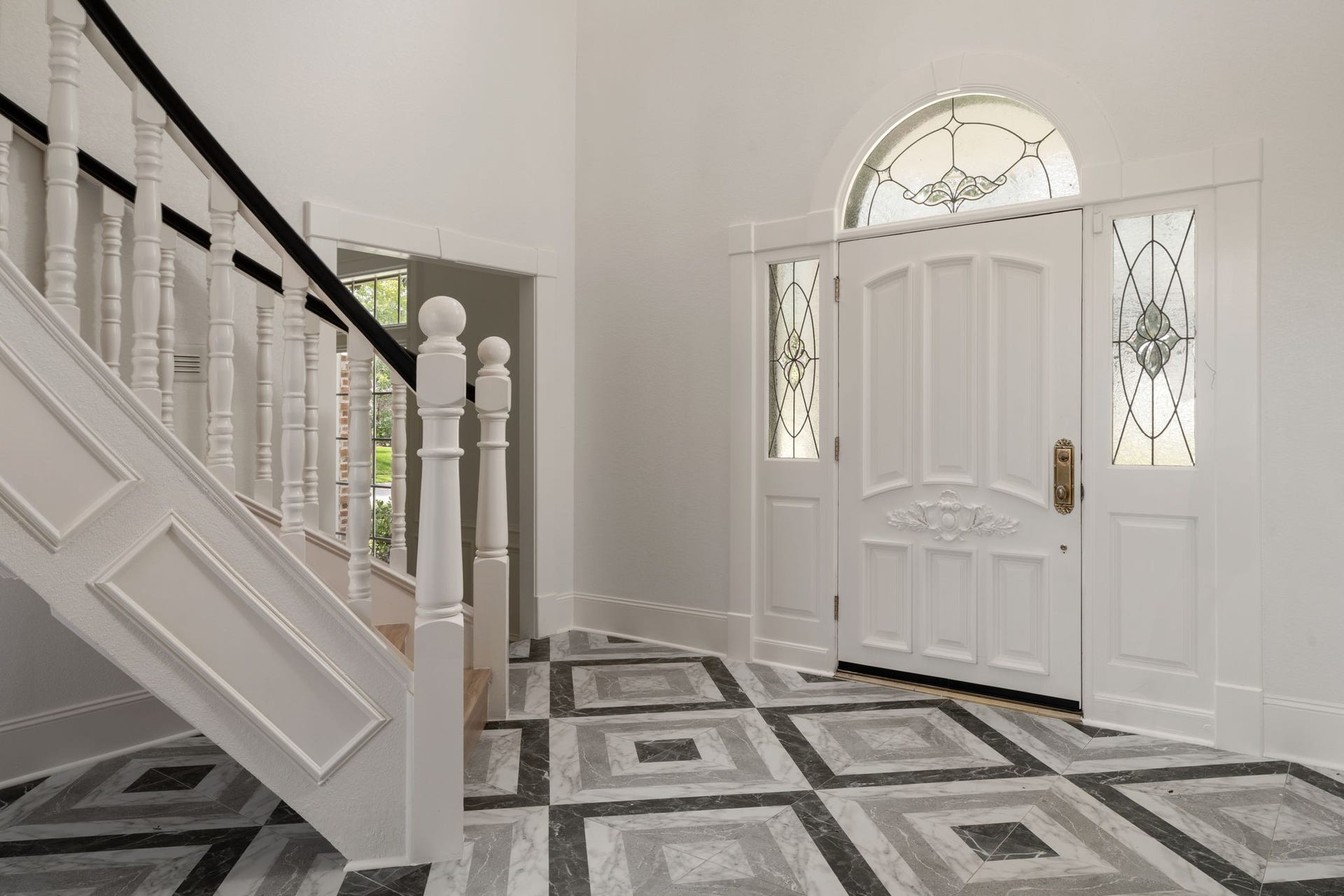 93 Greensward Lane, Sugar Land, TX 77479 A sweeping curved staircase anchors the two-story entry, creating a dramatic first impression upon arrival. Patterned tile flooring, oversized windows, and a renovated interior enhance the foyers architectural scale and natural light. Open sightlines connect the entry to the homes main living spaces.