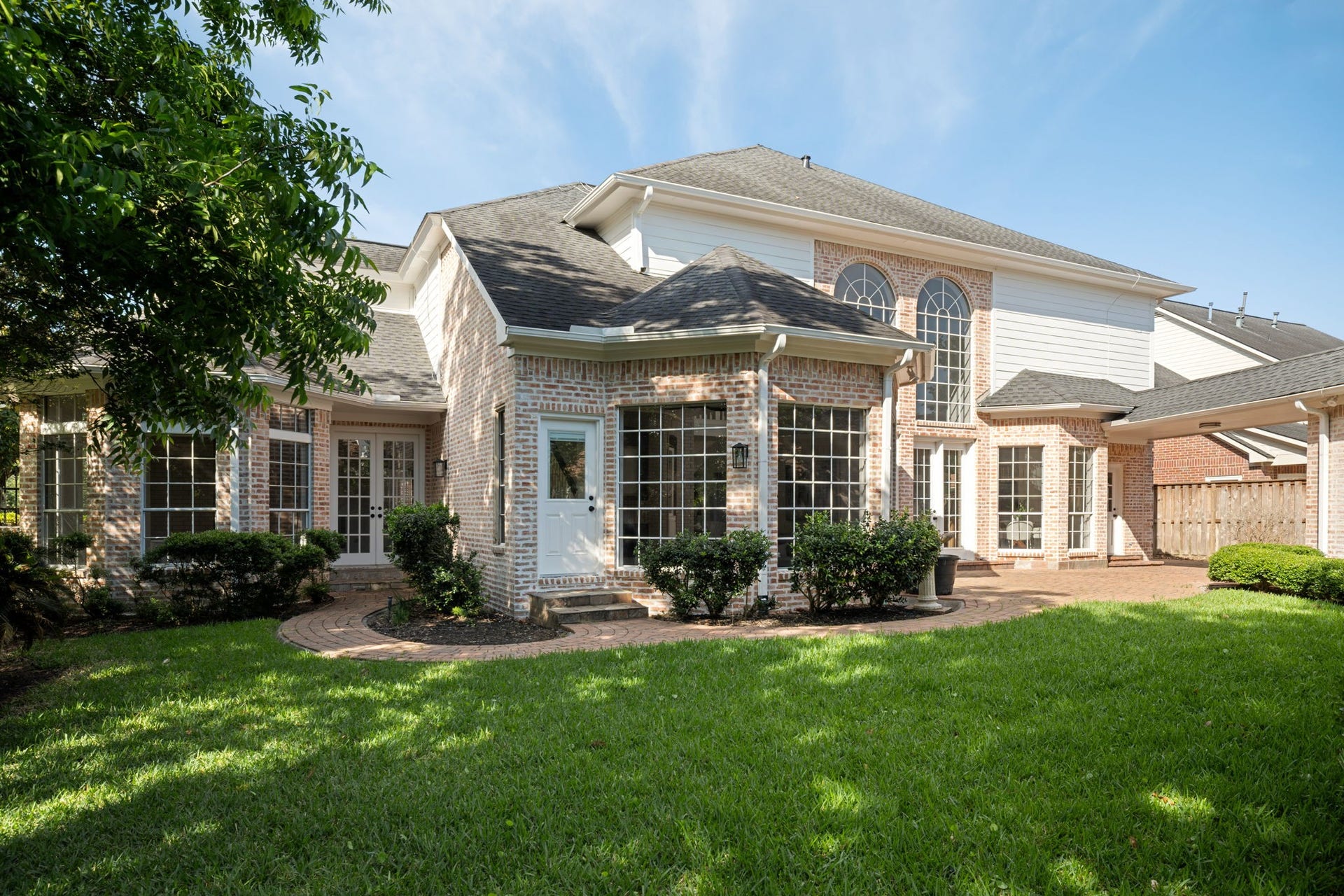 93 Greensward Lane, Sugar Land, TX 77479 The rear exterior balances classic architecture with updated presentation and established landscaping throughout the property. Expansive windows, elevated ceilings, and courtyard-style outdoor spaces reinforce the homes indoor-outdoor connection. Positioned within Sweetwater Section 1 in the heart of Sugar Land.