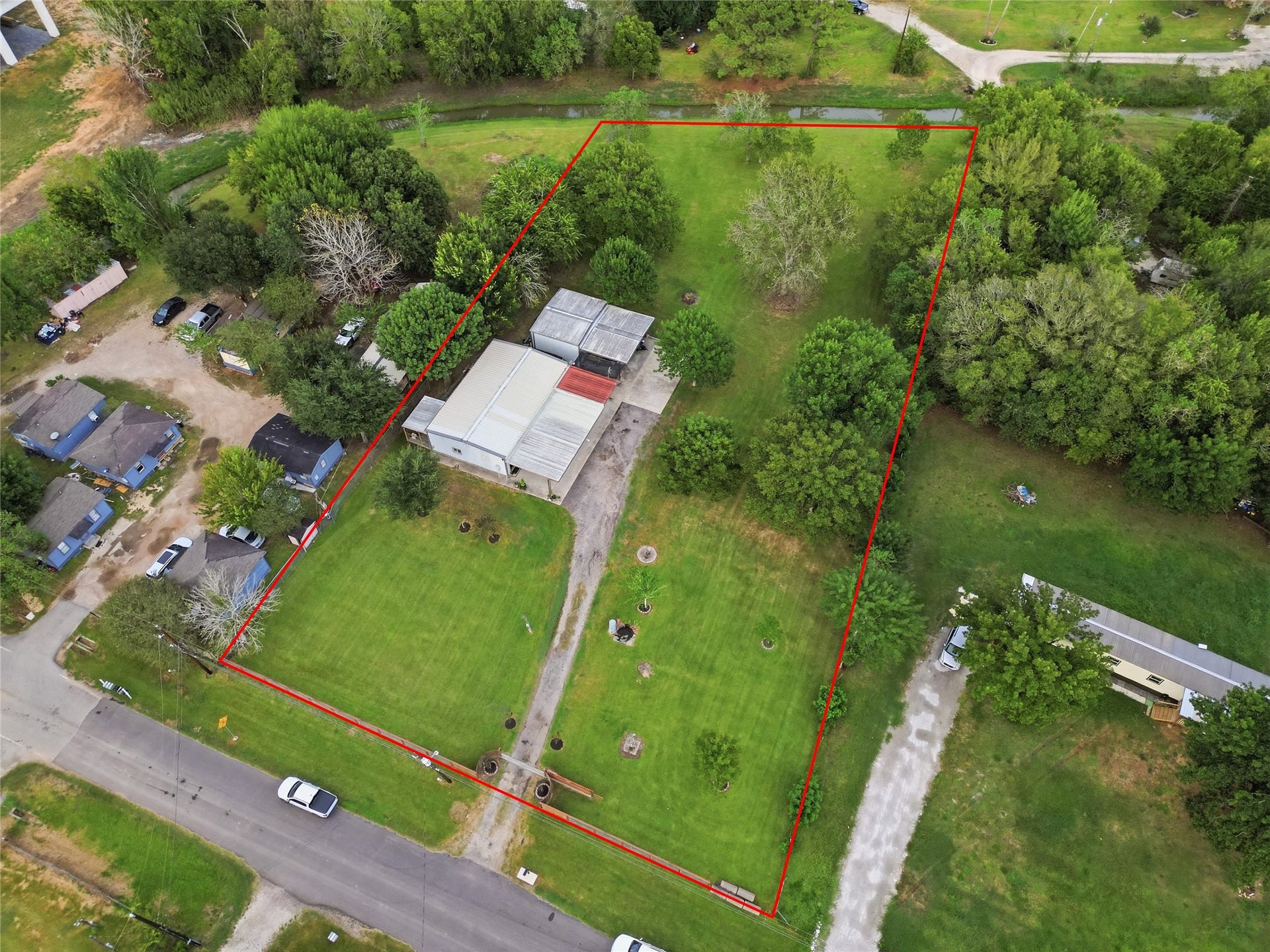 18503 Frazier Drive, #C176C, Pearland, TX 77584 Aerial view showcasing the expansive property, mature trees, large open lawn, driveway, residence, and surrounding out door space.