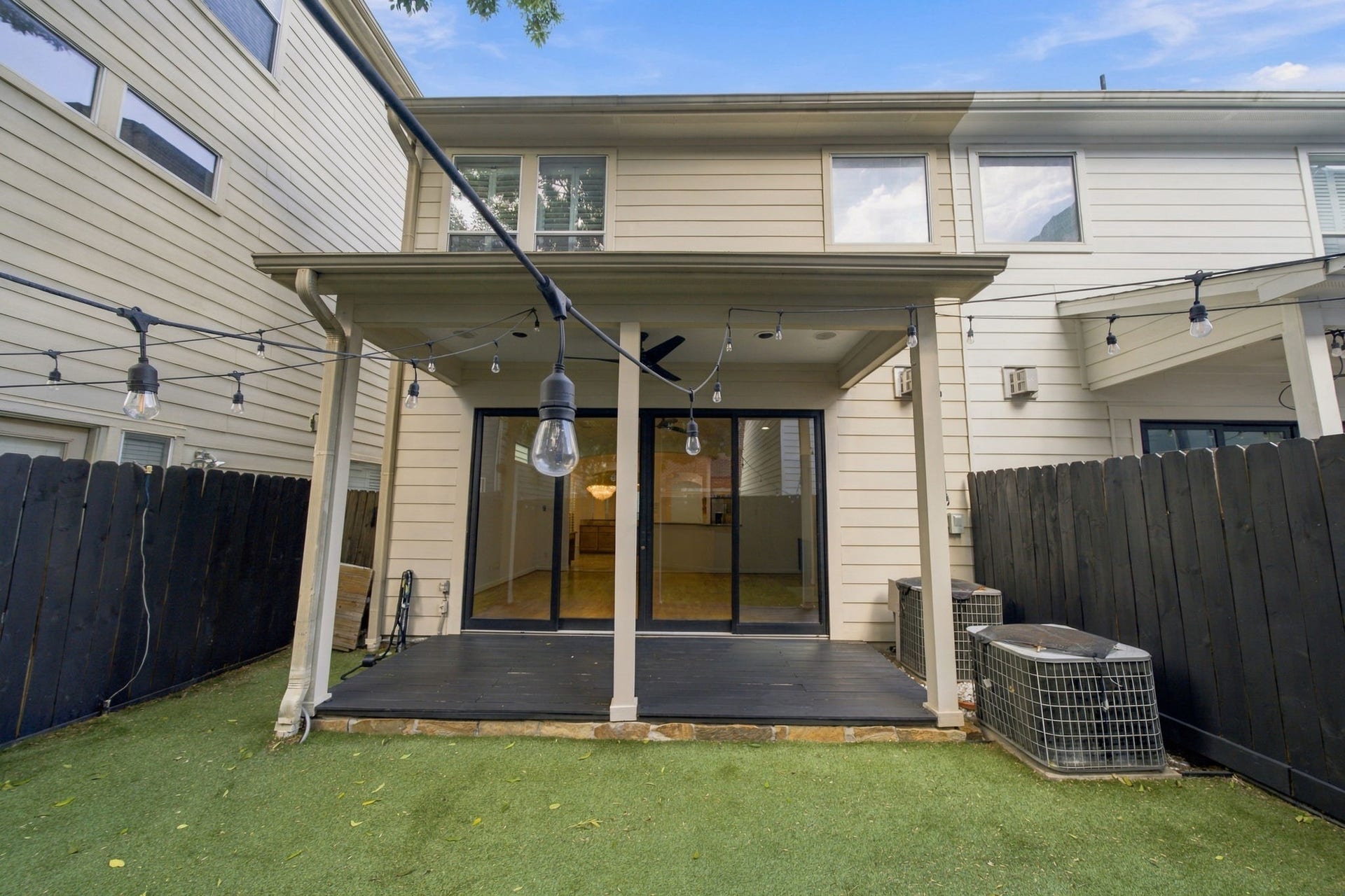 6113 Maxie Street, Houston, TX 77007 A covered patio extends the living space outdoors, with sliding glass doors connecting directly to the main living area. String lighting adds a charming touch for evenings outside.
