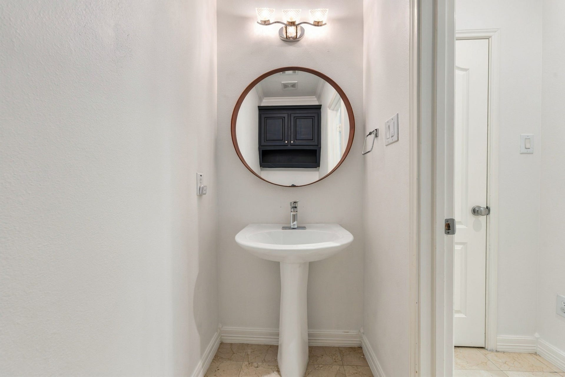 6113 Maxie Street, Houston, TX 77007 First-floor powder bath with a pedestal sink, contemporary fixtures & stylish round mirror.