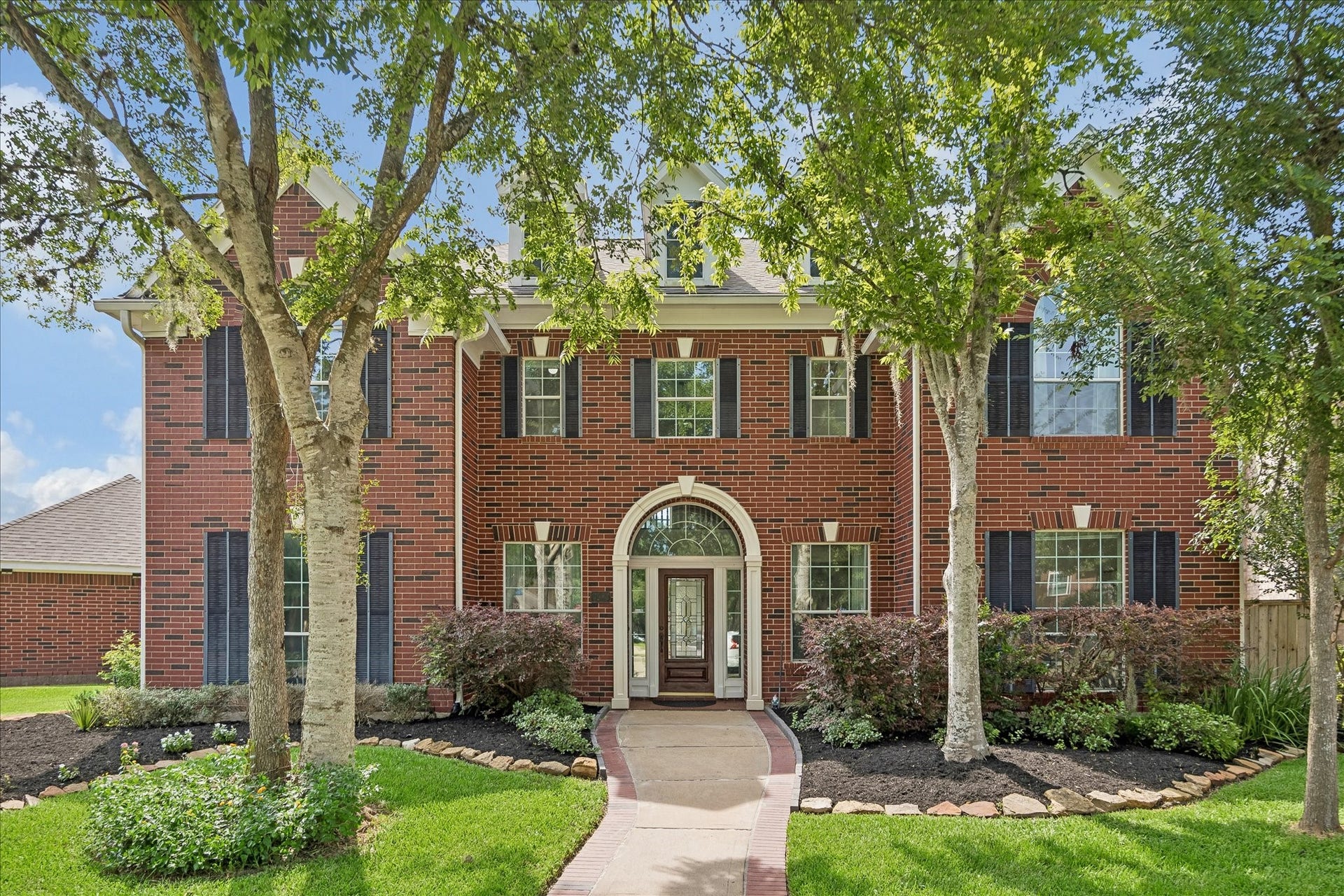 7503 Stone Arbor Drive, Sugar Land, TX 77479 A stately traditional brick exterior on a corner cul-de-sac lot ,elegant arched entry, and mature shade trees create a warm and impressive first impression. Meticulously maintained landscaping enhances the home's classic curb appeal.