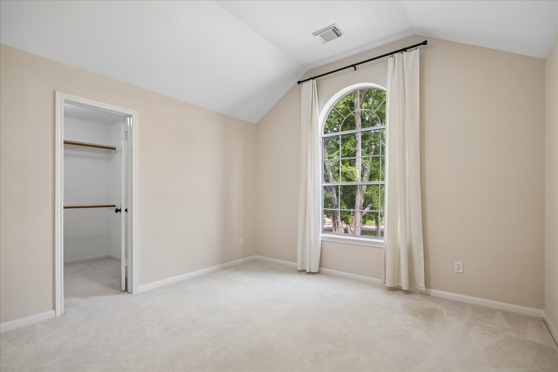 7503 Stone Arbor Drive, Sugar Land, TX 77479 Another secondary bedroom #5 showcases a charming arched window and convenient walk-in closet, offering both comfort and functionality for family or visitors.