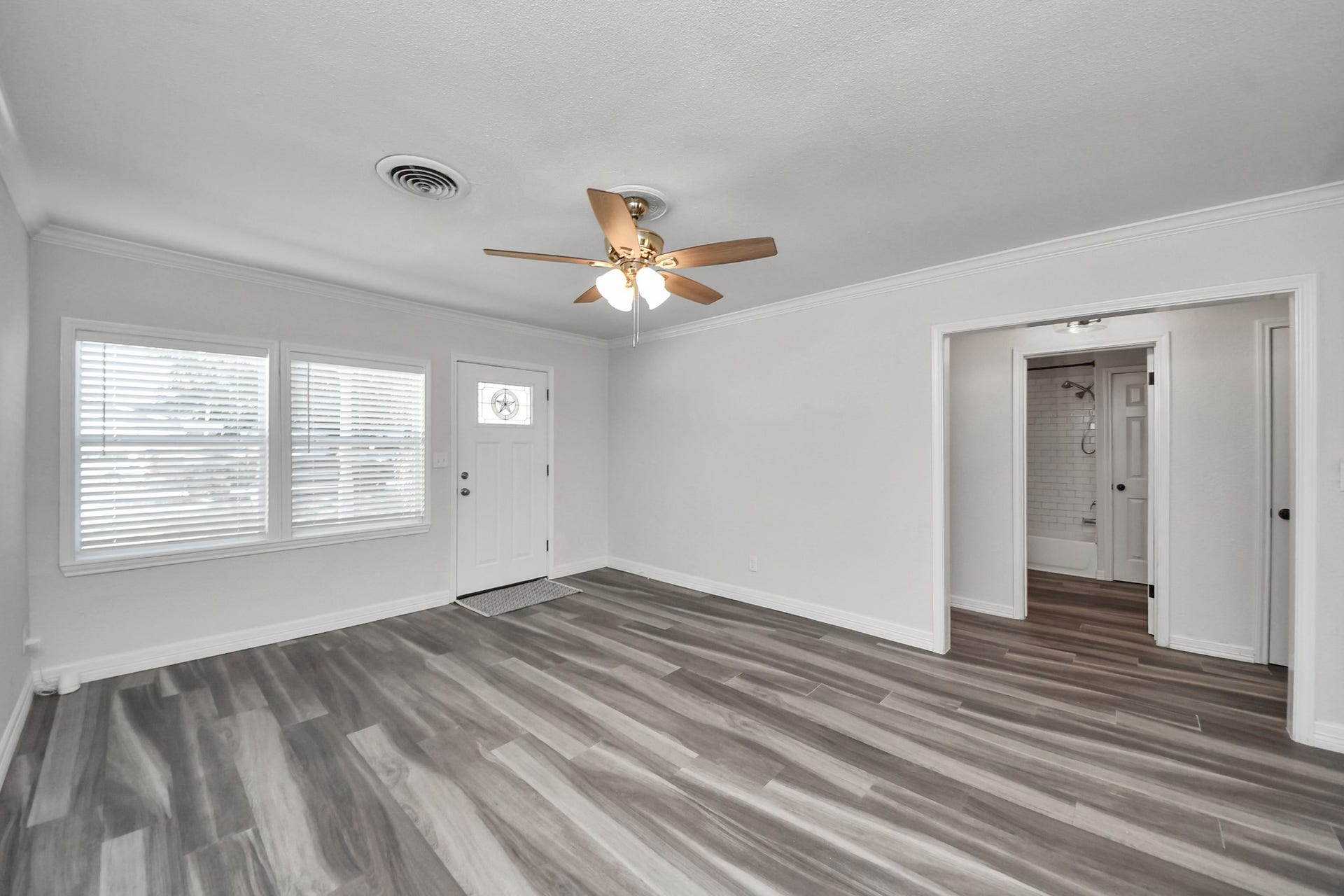 1309 W Lang Street, Alvin, TX 77511 Natural light from the front windows enters the open living room with a view to the hallway that leads to the two, secondary bedrooms and second full bathroom.