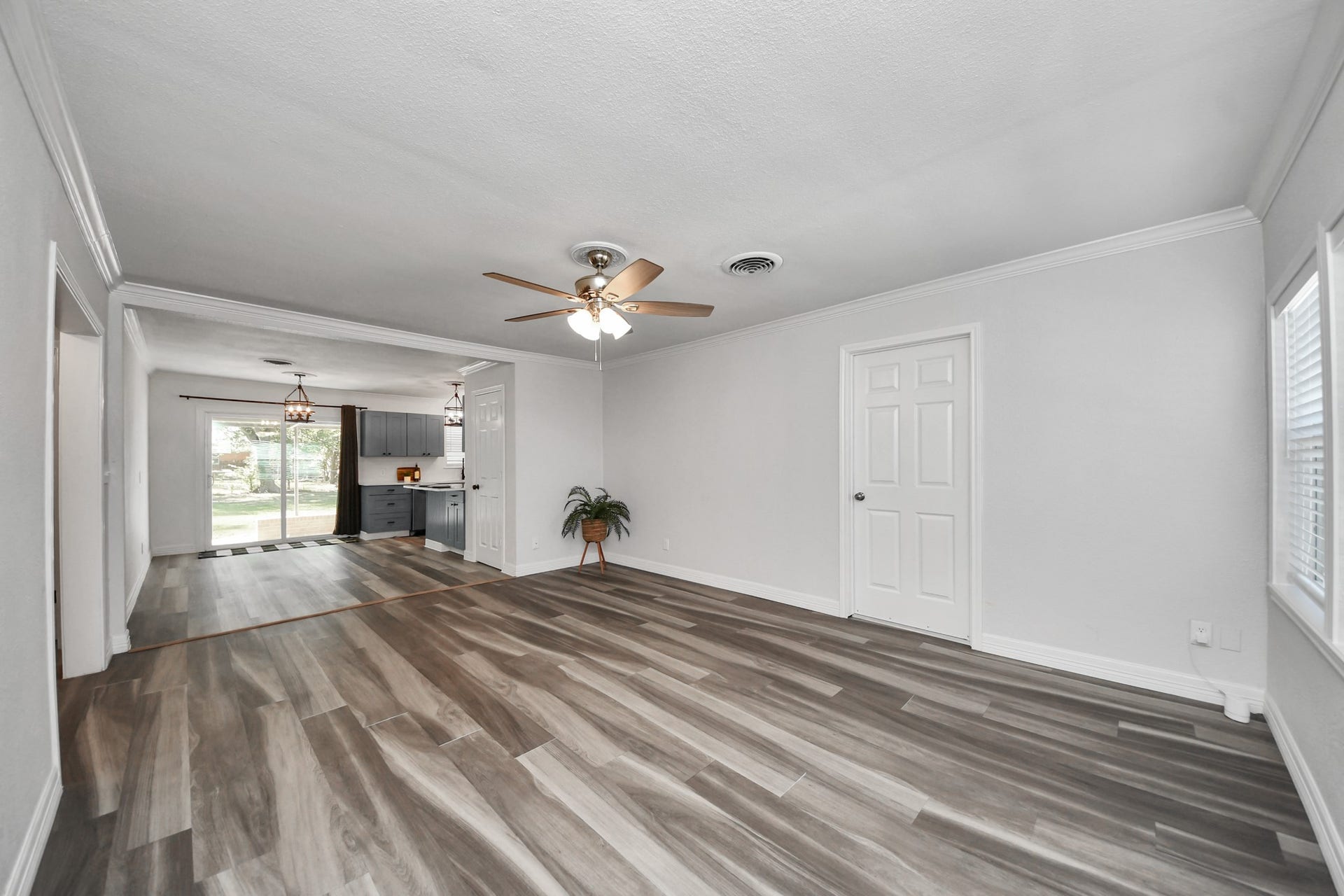 1309 W Lang Street, Alvin, TX 77511 Living Room with Wood-Look Laminate Flooring and open to the dining/kitchen area and easy access to the attached garage. The hallway to the left takes you to the secondary bedrooms and shared bathroom.