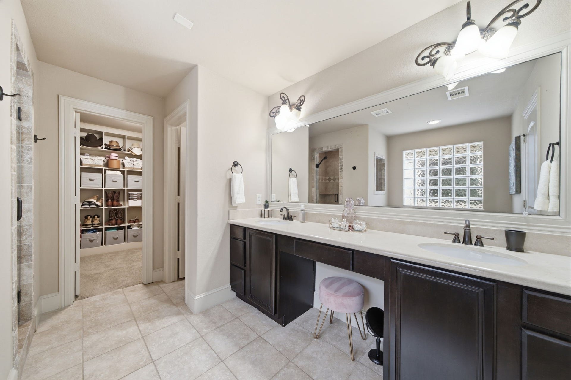 Primary bath offers dual sinks and a vanity area.  View to just one of the huge walk in closets this primary suite offers.
