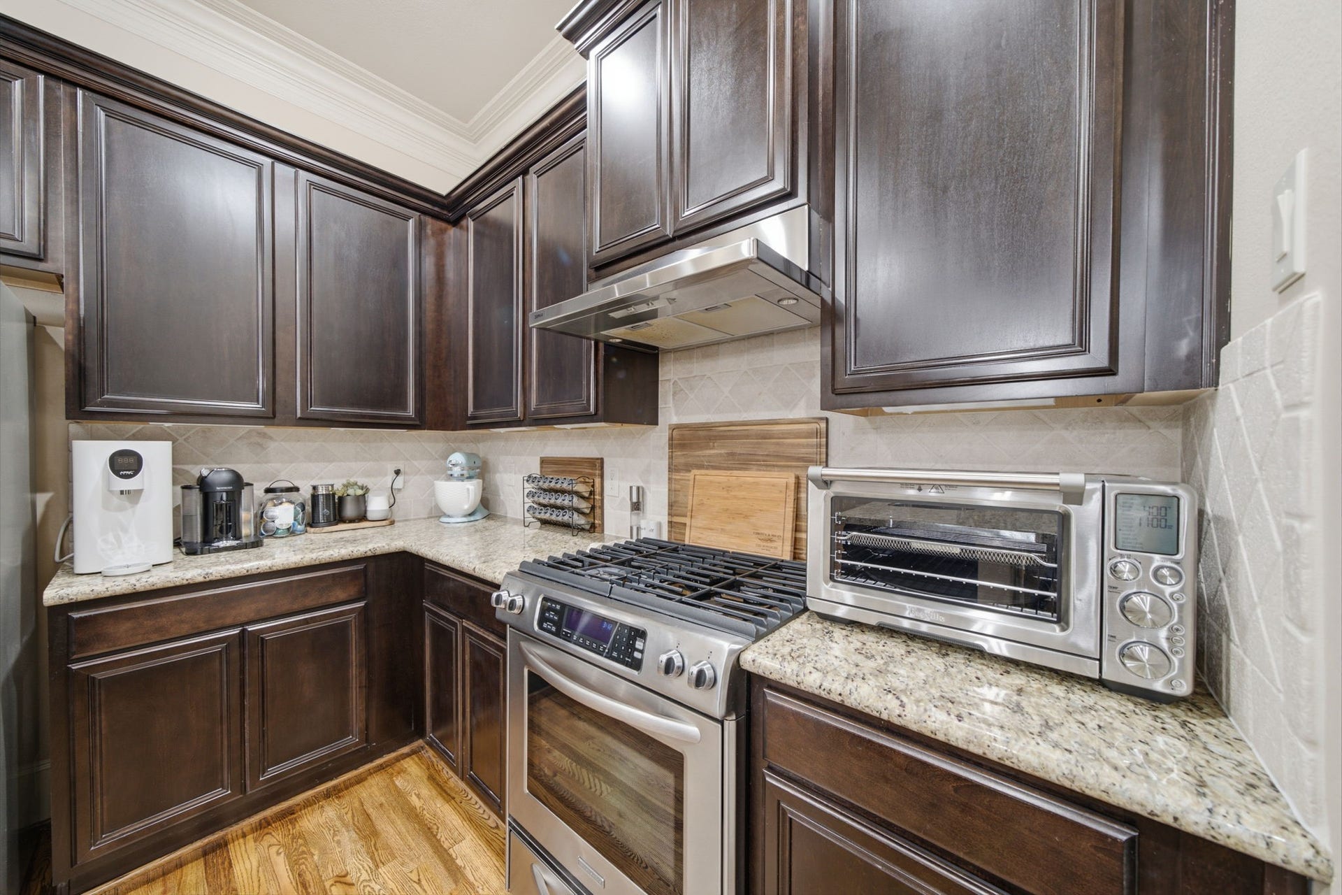 Stainless steel gas range with hood.  Tumbled marble backsplash and granite countertops.