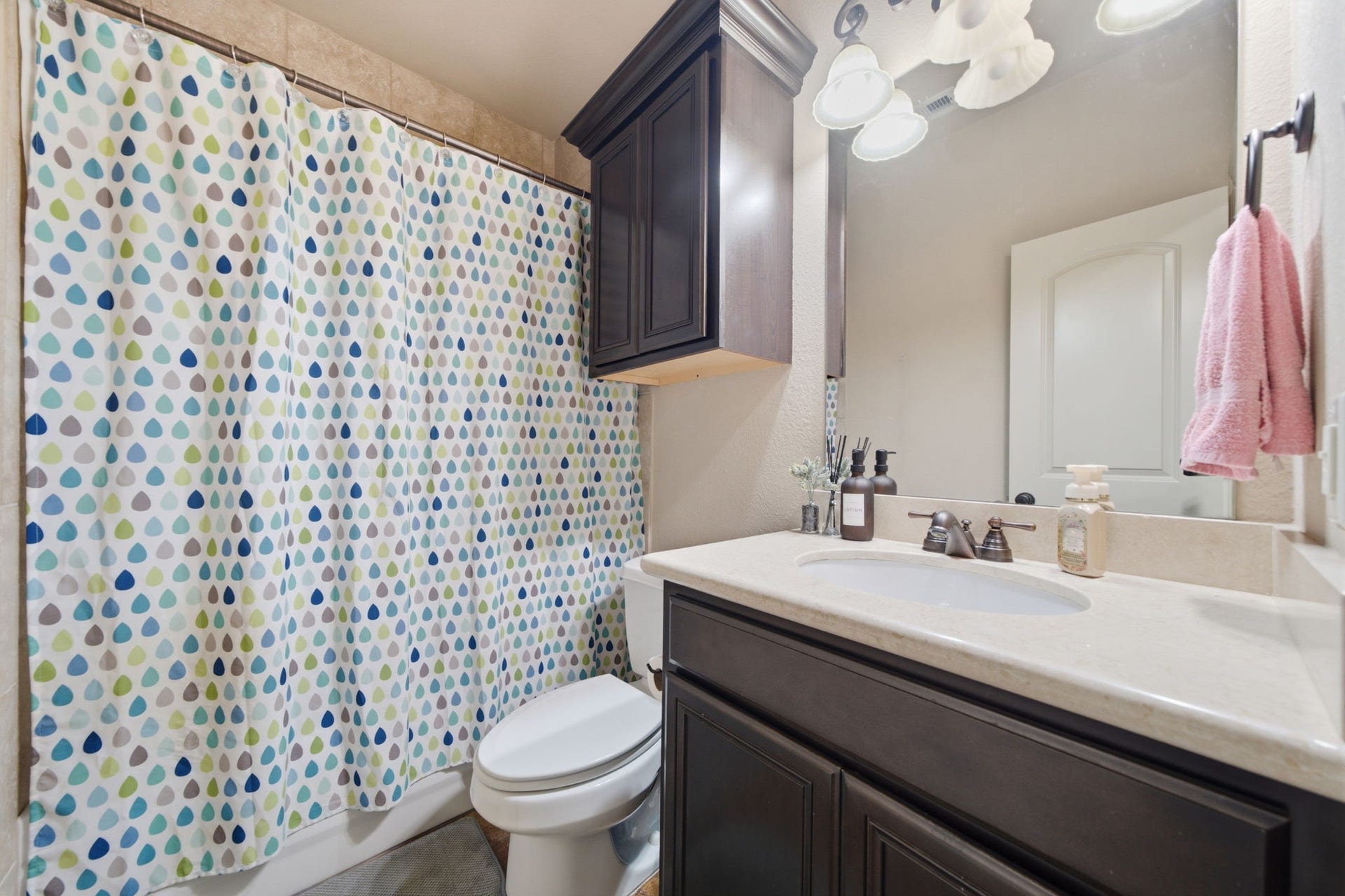 Full guest bathroom on 1st floor with marble countertop and travertine tiled tub/shower.