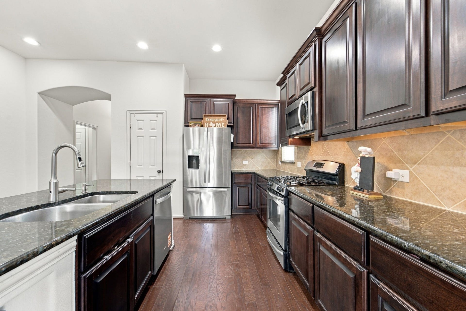 19011 Crest Cove Drive, Cypress, TX 77433 This well-organized kitchen offers generous counter space, tall cabinets, and wood floors that flow into the living area.