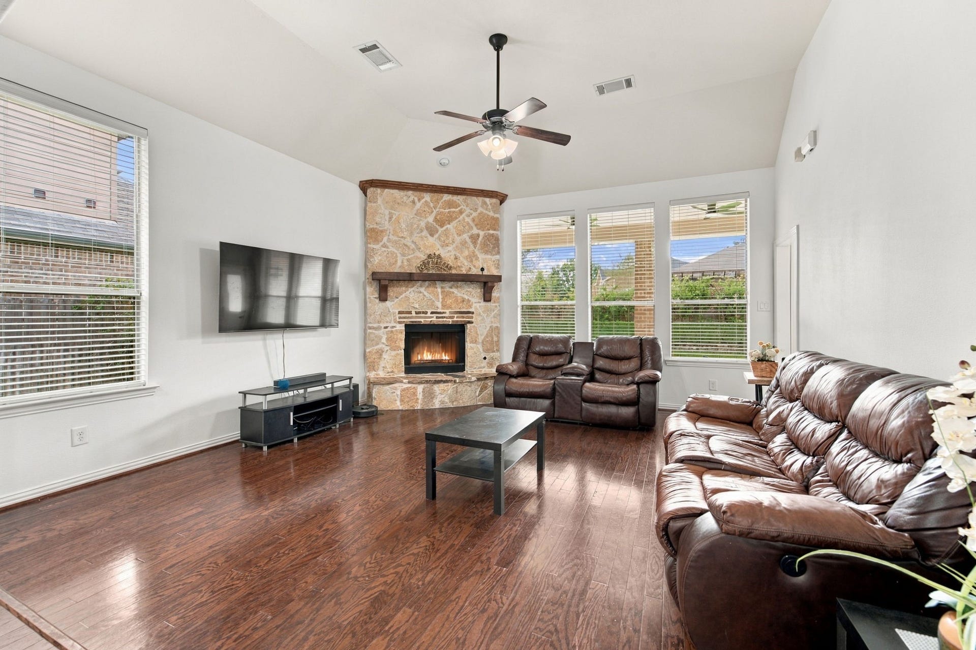 19011 Crest Cove Drive, Cypress, TX 77433 Vaulted ceilings give this generously sized living room an open, airy feel. The stone gas fireplace sets a cozy tone, and the windows bring in plenty of daylight, with easy access to the backyard through the back door.