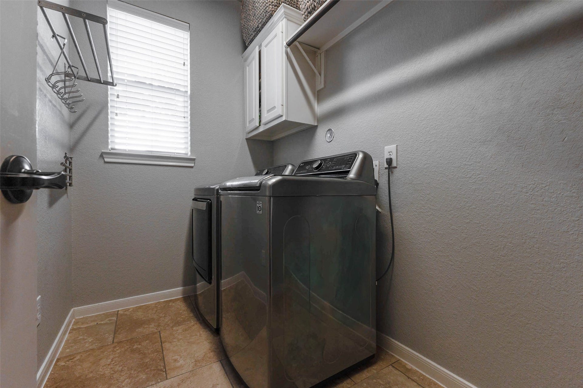 25734 Jewel Springs Lane, Katy, TX 77494 A dedicated laundry room combines overhead cabinetry, hanging space, and natural light for practical everyday convenience.