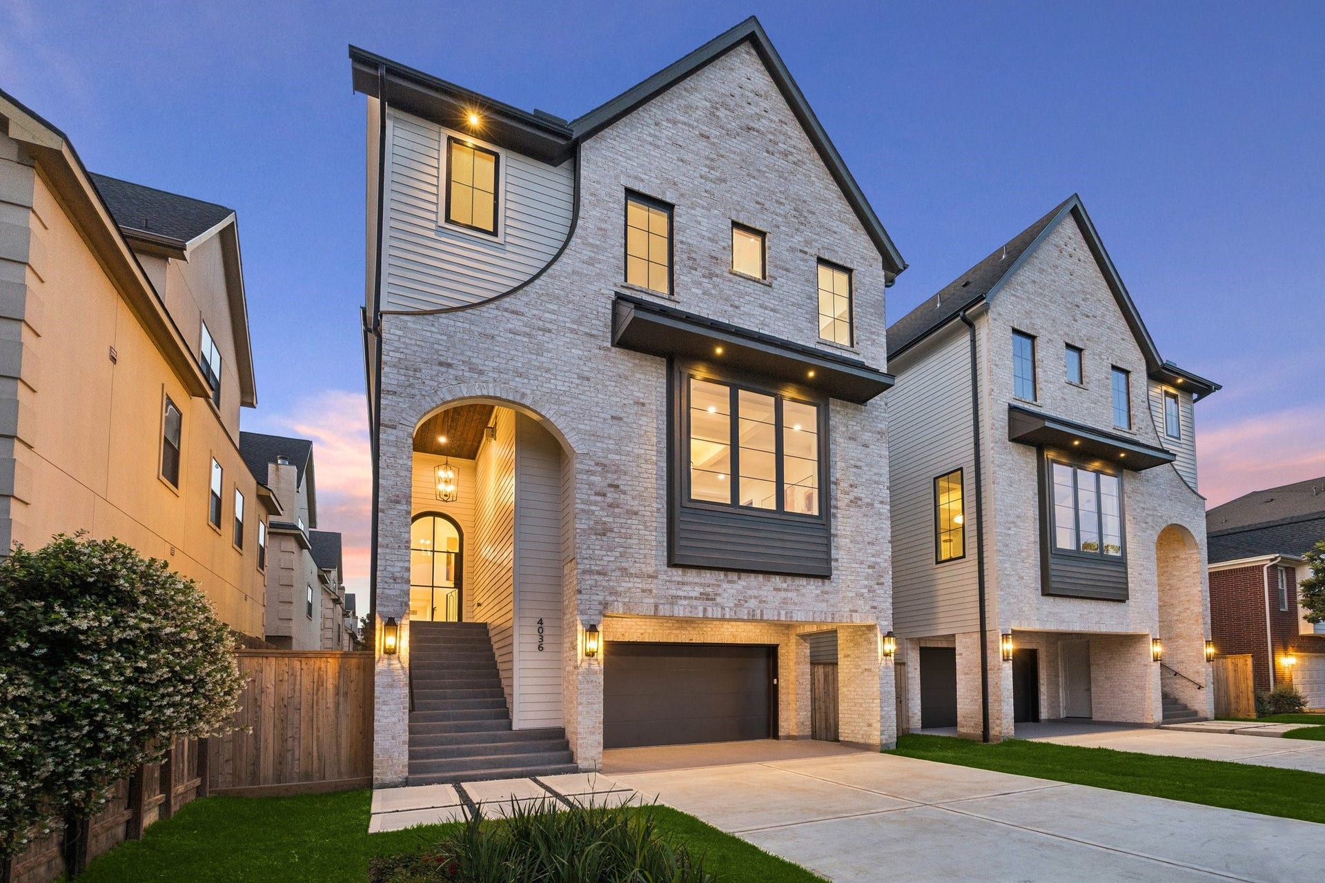 Another fantastic development from Prebisch Homes! This striking pair of Transitional residences feature a clean, symmetrical design with timeless architectural appeal. The facades are clad in Antique White Queen Brick, accented by dark trim and steep gabled rooflines. Large, black-framed windows punctuate the exterior, allowing abundant natural light while creating bold contrast against the light masonry.