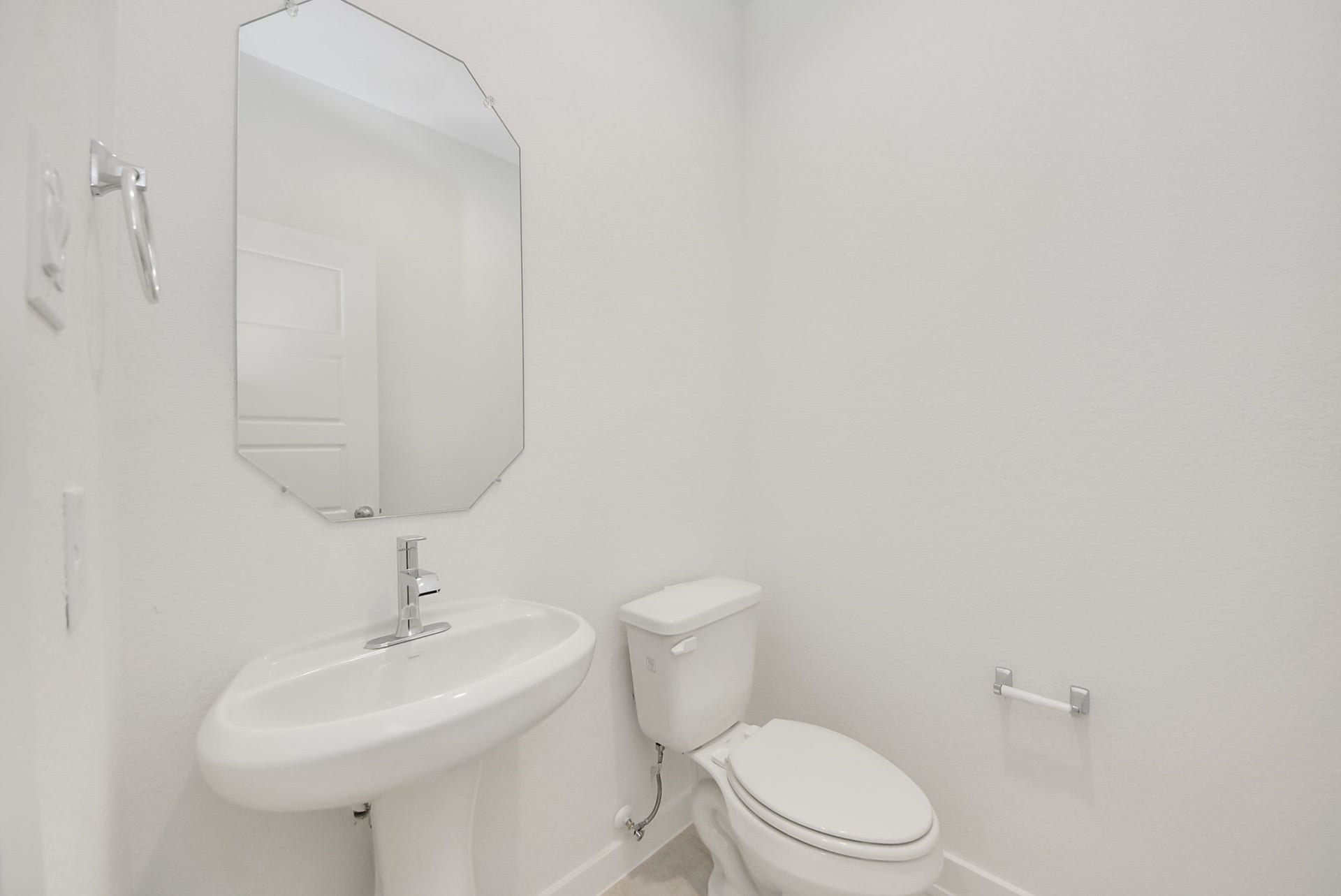 This half bathroom features a stylish pedestal sink, modern hardware, and bright recessed lighting, creating a sleek and inviting space.