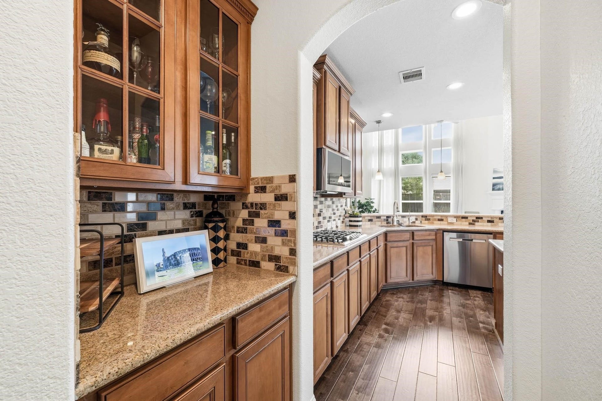 17610 Strackfield Lane, Tomball, TX 77377 Granite countertops and glass-front cabinetry elevate the butlers pantry, providing a sophisticated setting for entertaining essentials and organized storage.