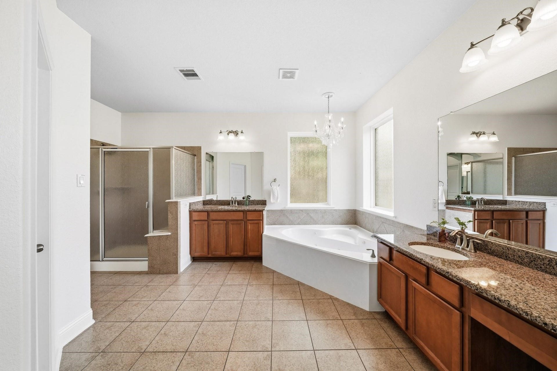 17610 Strackfield Lane, Tomball, TX 77377 Retreat to a beautifully appointed primary bath where dual sinks, granite counters, a makeup vanity, and elegant tile flooring create a refined space for daily routines.