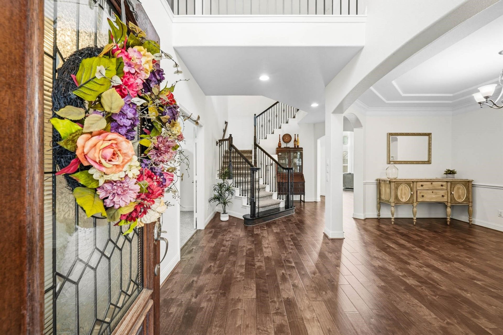 17610 Strackfield Lane, Tomball, TX 77377 A grand two-story foyer with rich hardwood floors creates a striking first impression, seamlessly connecting to the dining room through an elegant arched opening.