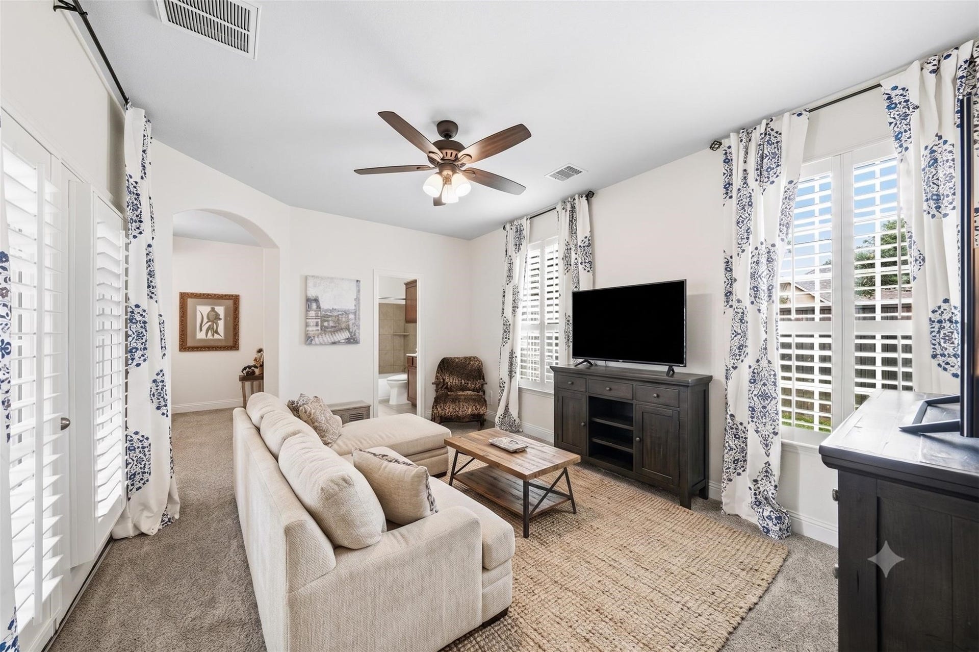 17610 Strackfield Lane, Tomball, TX 77377 Perfect for guests or multigenerational living, the private secondary suite begins with a charming sitting room filled with natural light, plantation shutters, elegant drapes, and direct access to the front porch through a 6-foot patio door. This photo has been virtually staged.