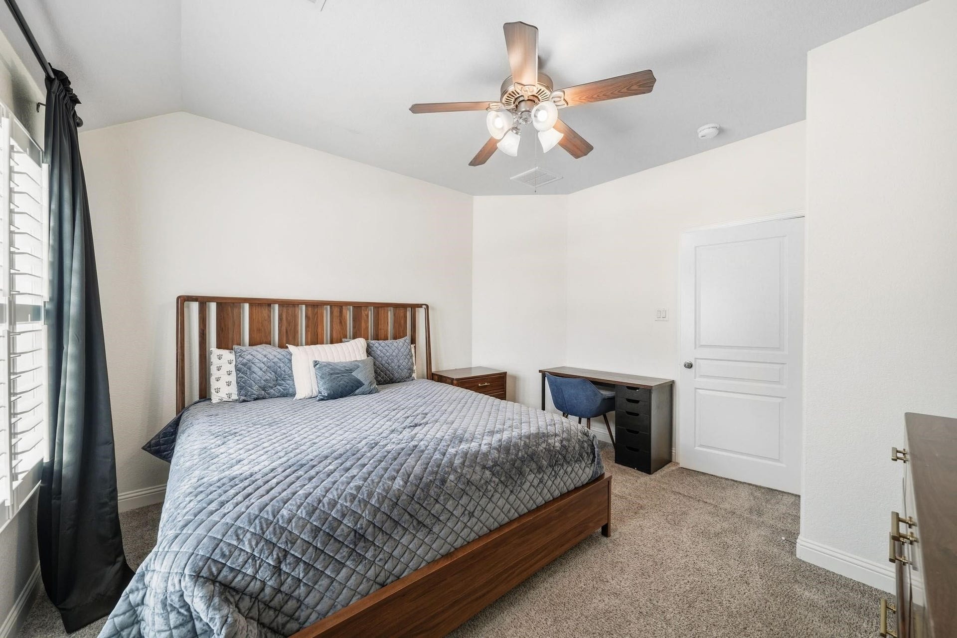 17610 Strackfield Lane, Tomball, TX 77377 Soft natural light filters through elegant plantation shutters, while a ceiling fan with integrated light enhances the inviting atmosphere of this peaceful third-bedroom retreat.