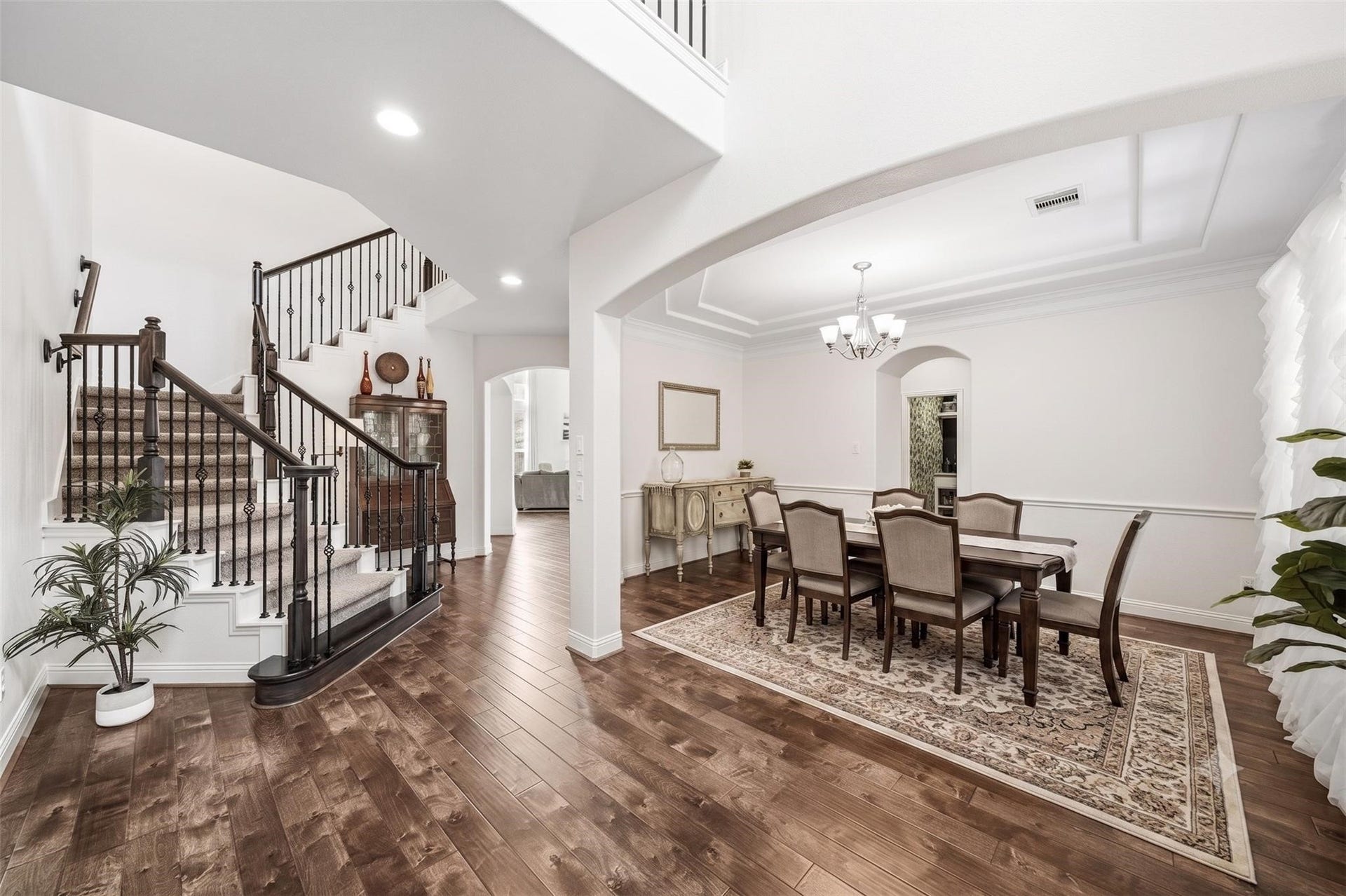 17610 Strackfield Lane, Tomball, TX 77377 The formal dining room exudes classic elegance with double crown molding and has a beautifully appointed chandelier as its centerpiece. The arched doorway leads to the pantry and Butler's pantry.The wrought iron staircase leads to the upstairs. This photo has been virtually staged.