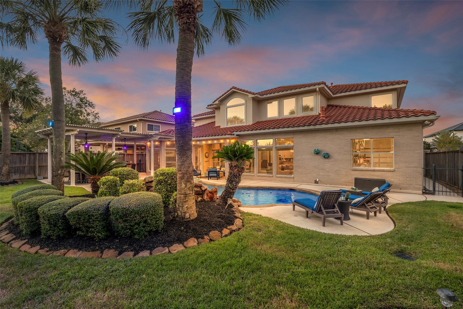 19023 Windsor Lakes Drive, Houston, TX 77094 Lush tropical landscaping with palms, sculpted hedges and installed landscape lighting for beautiful evenings outdoors