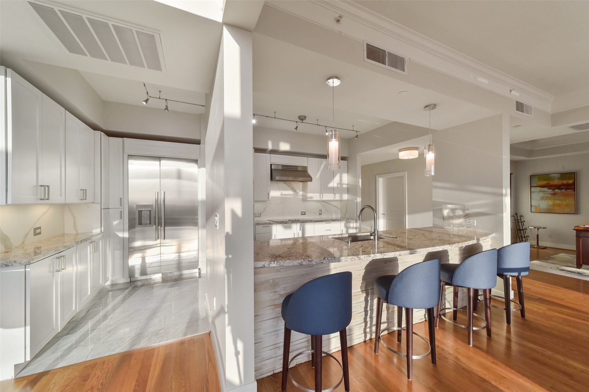 3333 Allen Parkway, #3003, Houston, TX 77019 Modern kitchen with Thermador appliances, ample cabinetry, and sleek granite countertops. Open floor plan with breakfast bar seating and pendant lighting, merging into the living and dining areas.