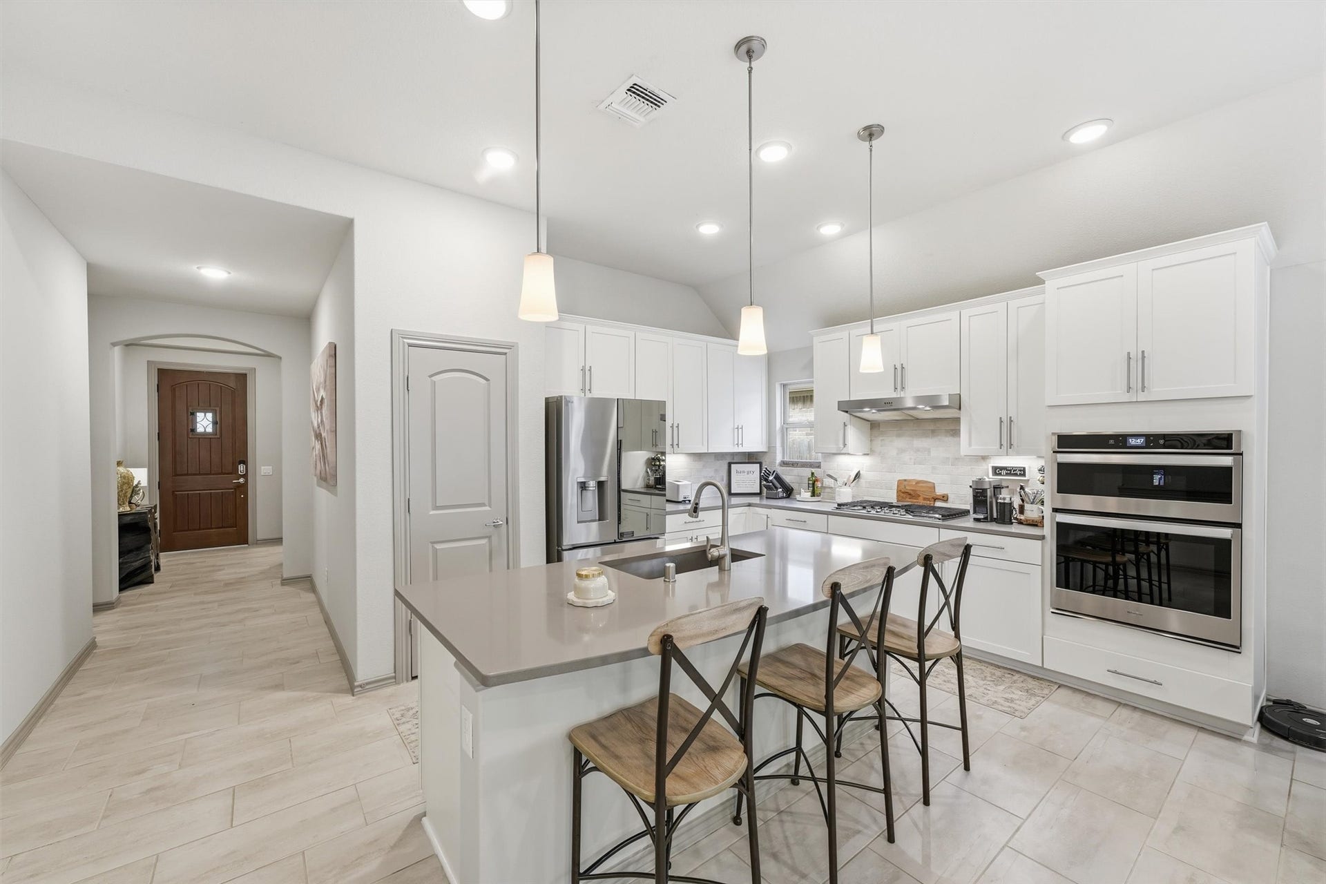 9726 Birdsnest Court, Spring, TX 77379 Beautifully appointed kitchen featuring white cabinetry, stainless steel appliances, a large center island, and stylish pendant lighting.