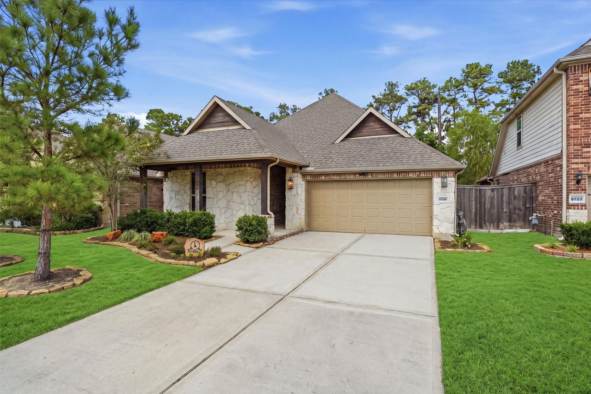 9726 Birdsnest Court, Spring, TX 77379 Beautiful single-story home featuring a stone-and-brick exterior, welcoming covered entry, manicured landscaping, and a two-car garage.