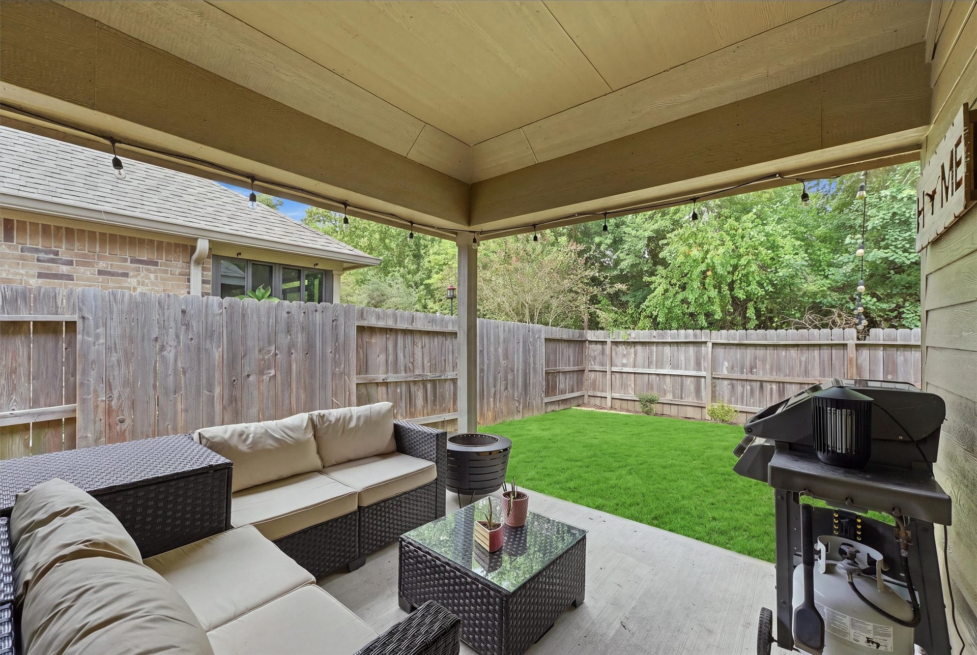 9726 Birdsnest Court, Spring, TX 77379 Inviting covered patio with outdoor seating, string lighting, and grilling area overlooking the private, fenced backyard.