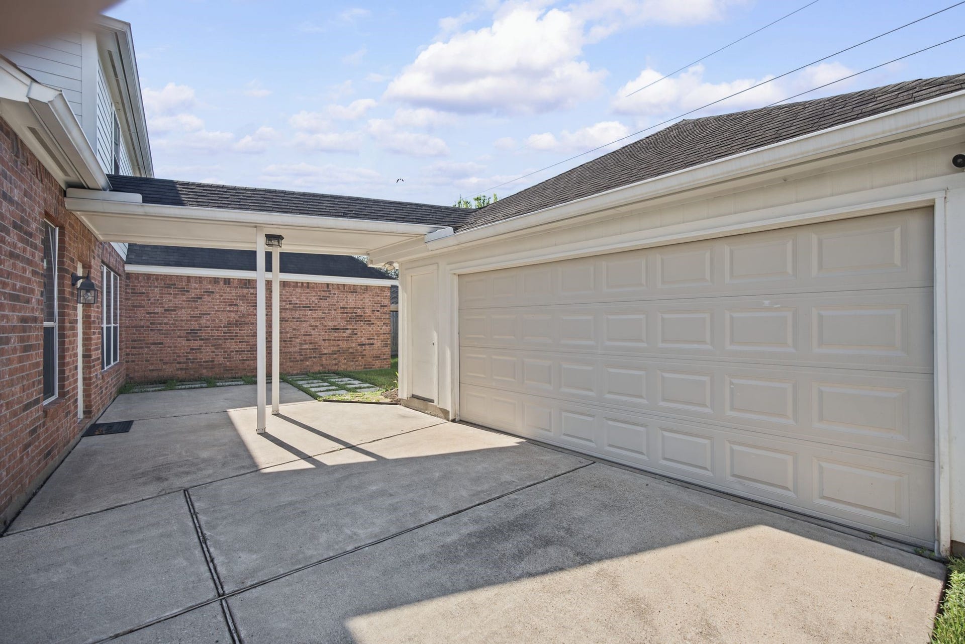 A closer perspective highlights the garage's wide overhead door and the sheltered passage along side the home.