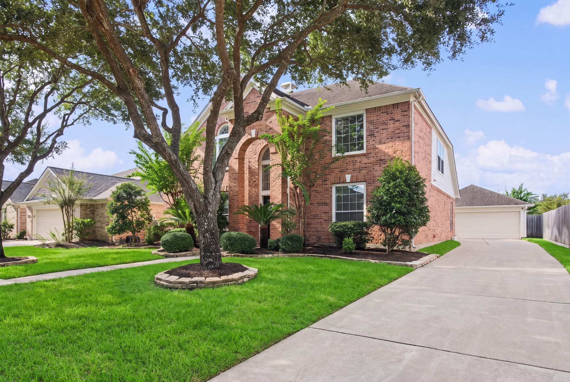 Along the side of the home, an extended driveway leads toward a 2-car detached garage, with a covered walkway to the home.