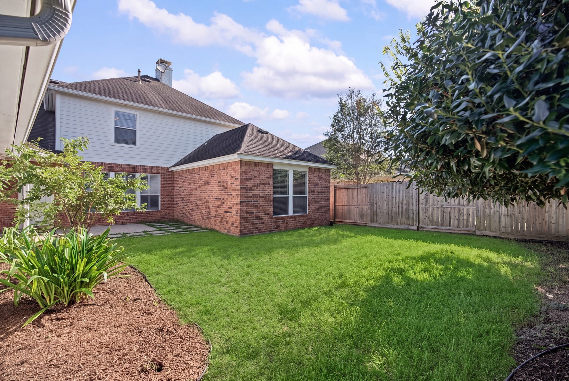 The backyard offers a welcoming outdoor setting, with mature trees, established planting beds, and room to enjoy the open lawn.