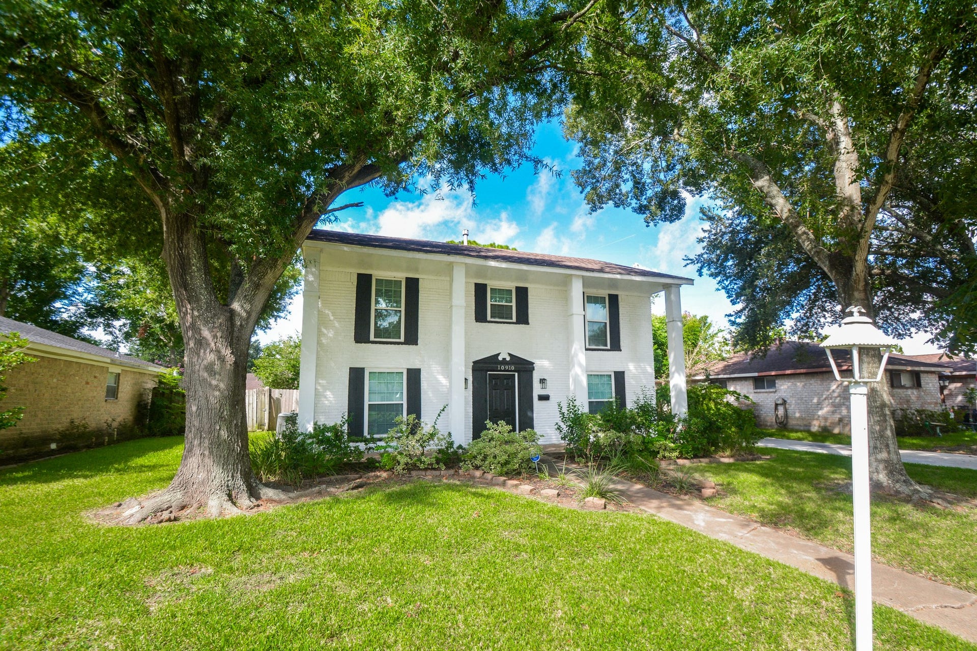 Grand view of the home with sprawling front lawn and trees for shade.