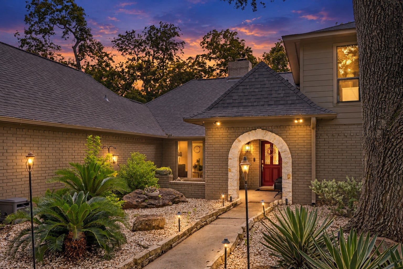 2020 PECAN LAKE DRIVE, Richmond, TX 77406 COVERED ARCHED ENTRY IS COMPLEMENTED BY MATURE LANDSCAPING, STONE ACCENTS, AND A LANDSCAPED COURTYARD-STYLE APPROACH.