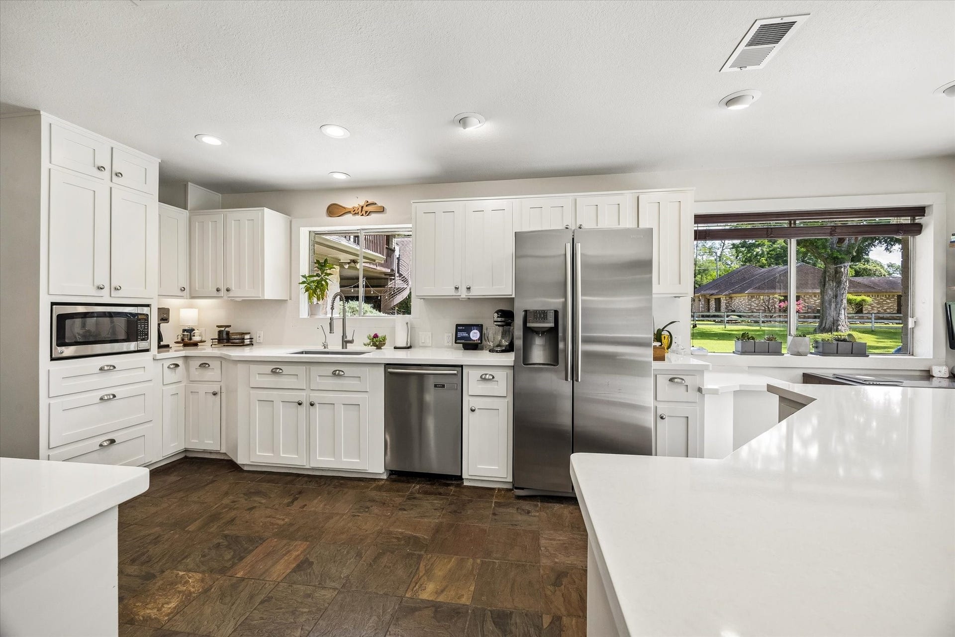 2020 PECAN LAKE DRIVE, Richmond, TX 77406 SPACIOUS KITCHEN OFFERS EXTENSIVE WHITE CABINETRY, GENEROUS COUNTER SPACE, STAINLESS STEEL APPLIANCES, AND LARGE WINDOWS OVERLOOKING THE GROUNDS.