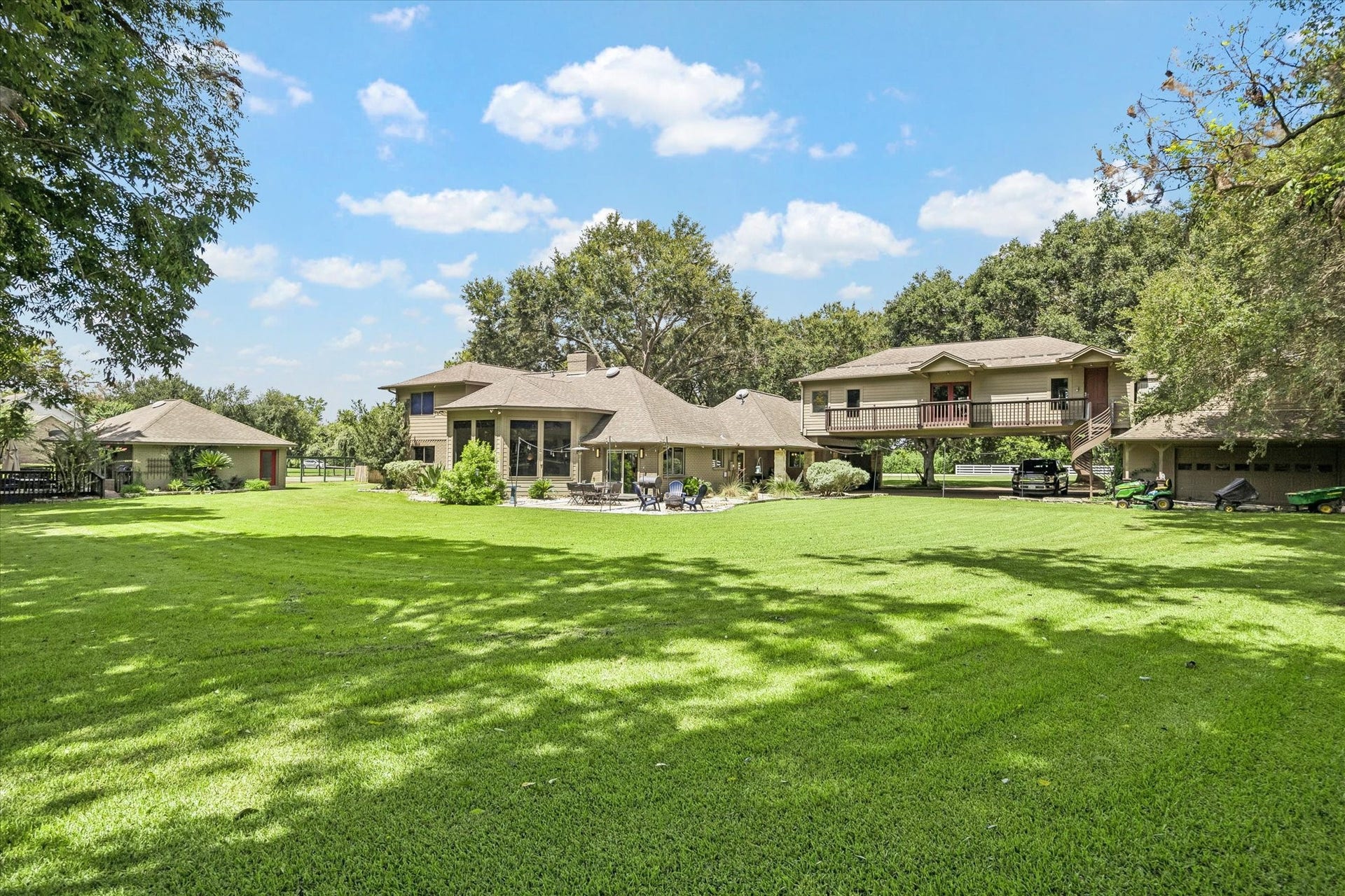 2020 PECAN LAKE DRIVE, Richmond, TX 77406 WIDE REAR VIEW SHOWCASES THE HOME, EXPANSIVE GROUNDS, MATURE LANDSCAPING, AND MULTIPLE EXTERIOR STRUCTURES.