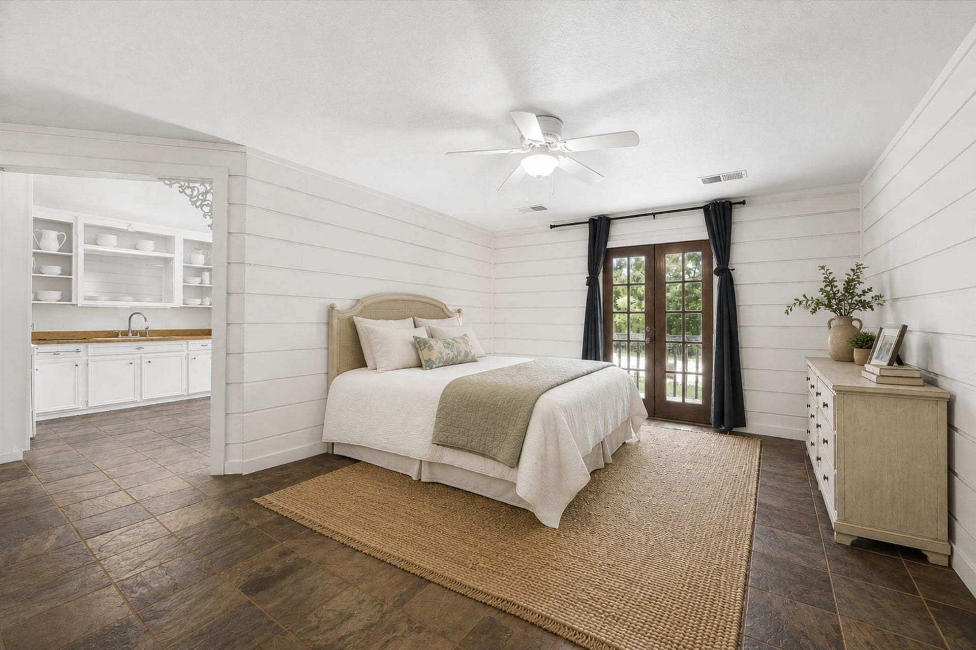 2020 PECAN LAKE DRIVE, Richmond, TX 77406 GUEST HOUSE BEDROOM FEATURES SHIPLAP-STYLE WALL DETAILING, TILE FLOORING, CEILING FAN, AND FRENCH DOORS PROVIDING EXTERIOR ACCESS.