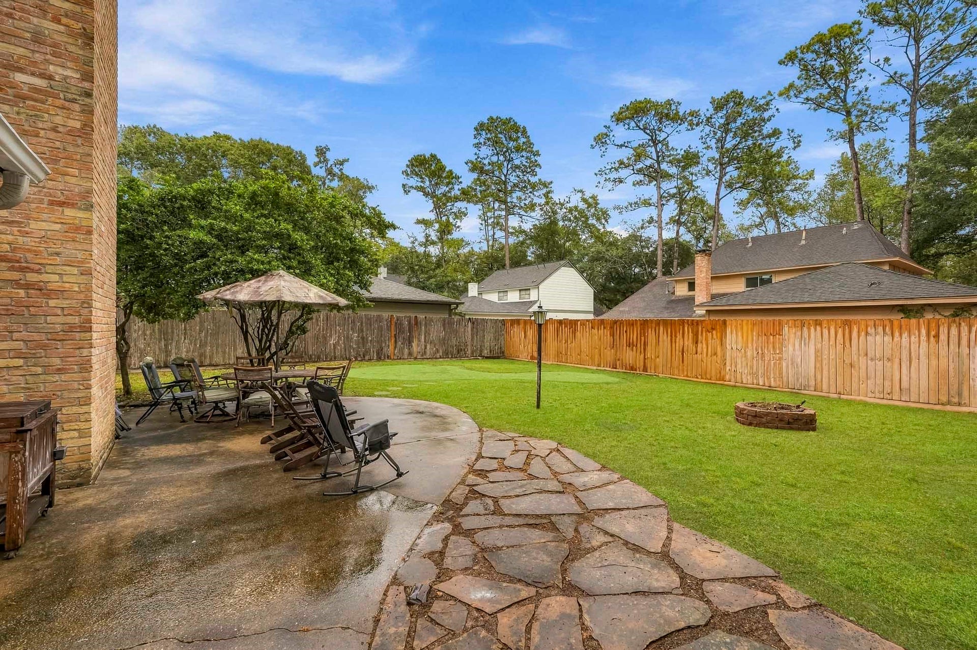 3610 Valley Haven Drive, Houston, TX 77339 Spacious backyard featuring a large patio with seating area, perfect for outdoor entertaining, surrounded by lush greenery and a cozy fire pit for evening relaxation.
