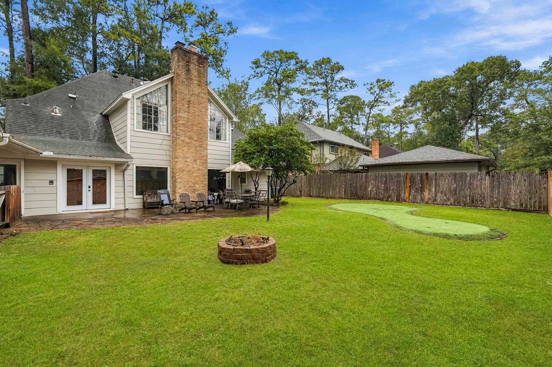 3610 Valley Haven Drive, Houston, TX 77339 Beautiful backyard featuring a spacious lawn, cozy fire pit, and patio area perfect for outdoor gatherings, all set against a backdrop of mature trees.