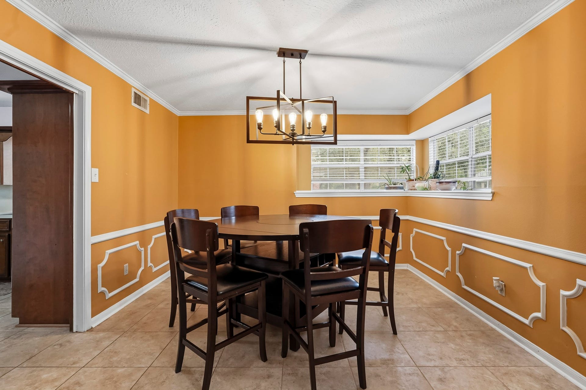 3610 Valley Haven Drive, Houston, TX 77339 Bright dining area with elegant wainscoting, and a stylish chandelier, offering ample natural light through large corner windows.