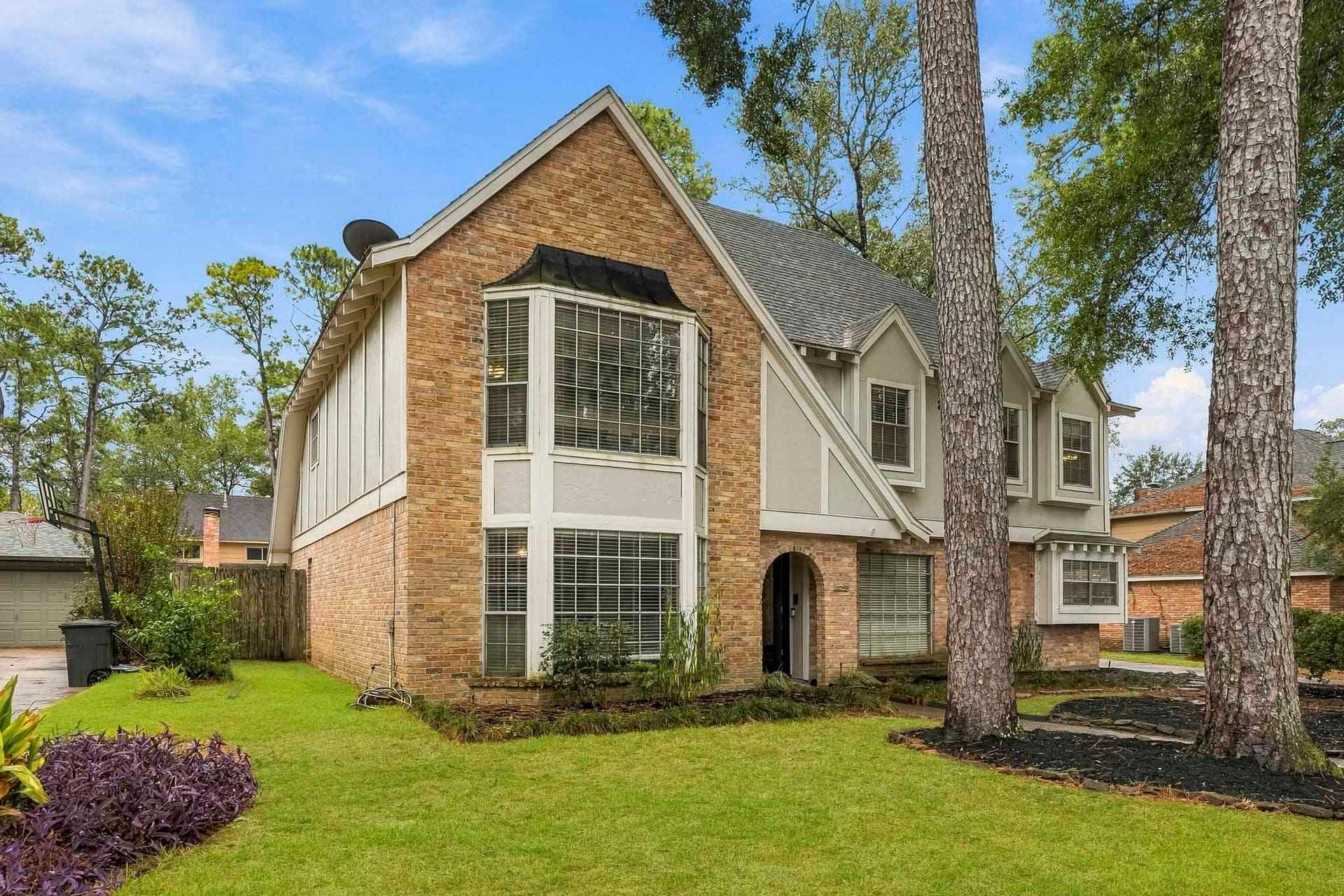 3610 Valley Haven Drive, Houston, TX 77339 Charming two-story brick home with large bay windows, nestled among mature trees, offering a spacious front lawn and inviting curb appeal.