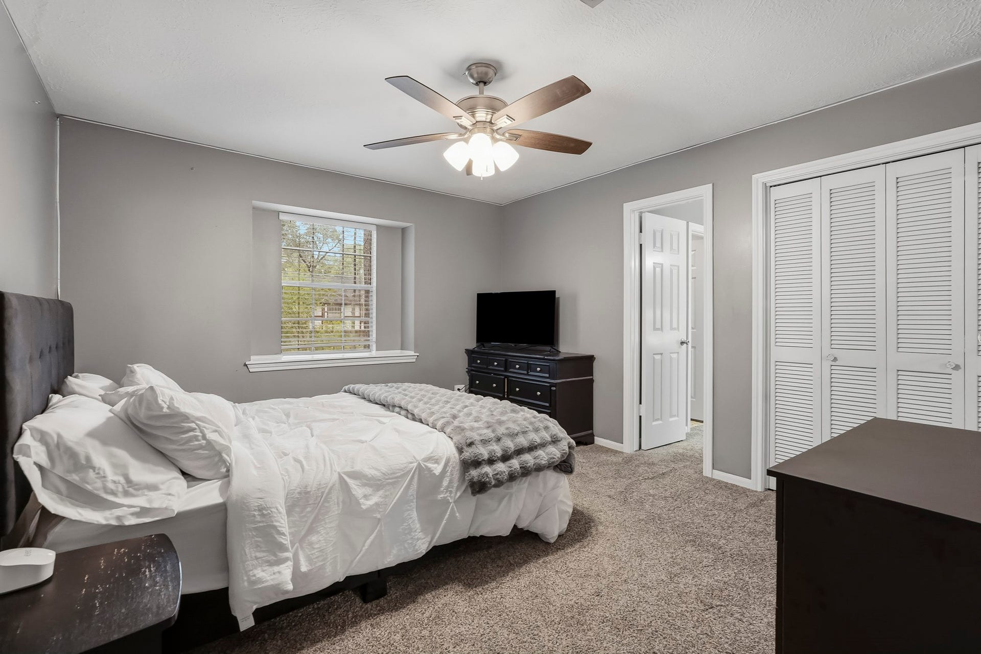 3610 Valley Haven Drive, Houston, TX 77339 Spacious third bedroom with soothing gray walls, plush carpeting, and a ceiling fan. Features a large window for natural light, ample closet space, and an en-suite bathroom.