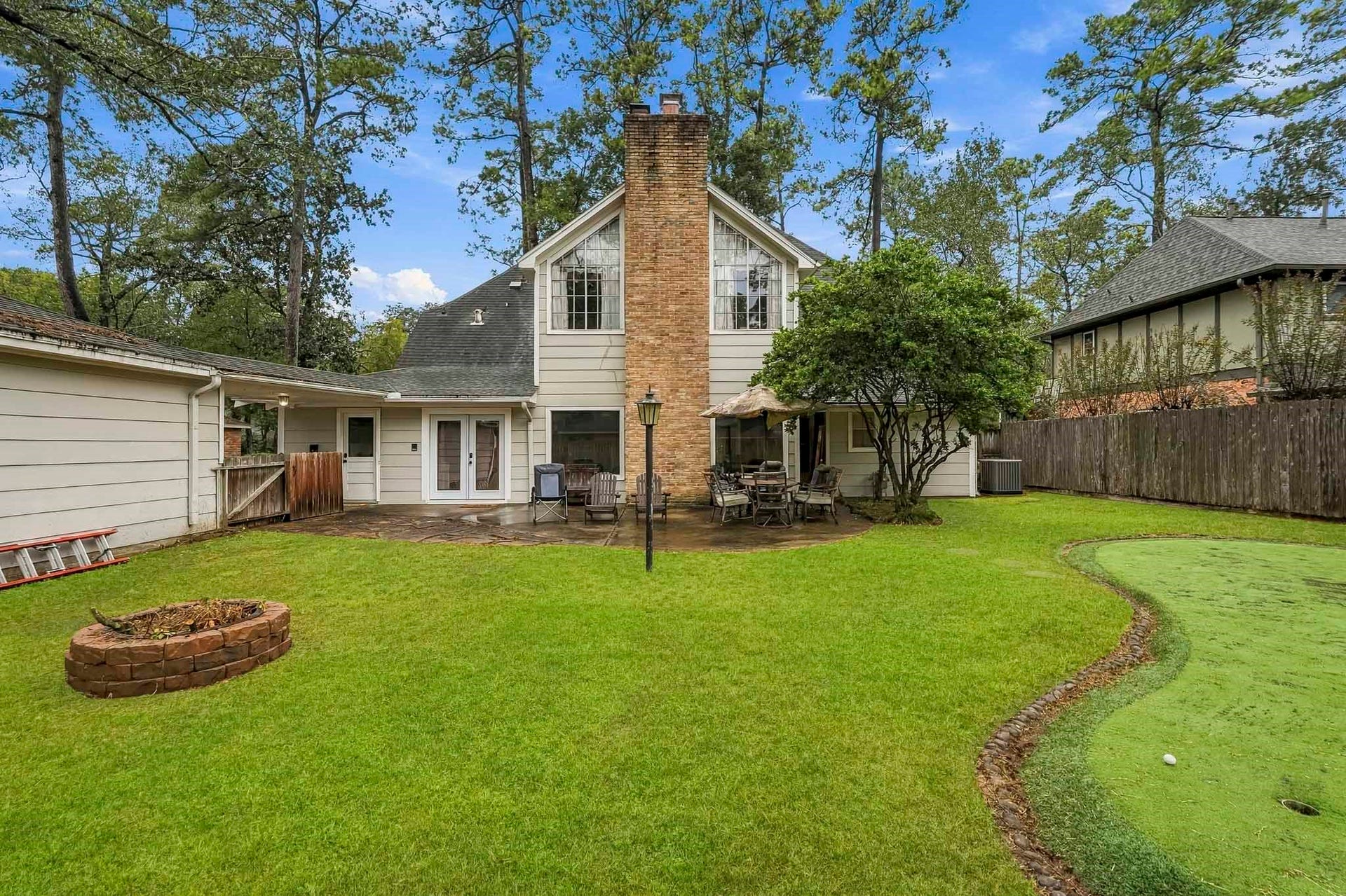 3610 Valley Haven Drive, Houston, TX 77339 Charming backyard retreat featuring a spacious patio, lush greenery, a cozy fire pit, and a putting green, perfect for outdoor entertaining and relaxation.